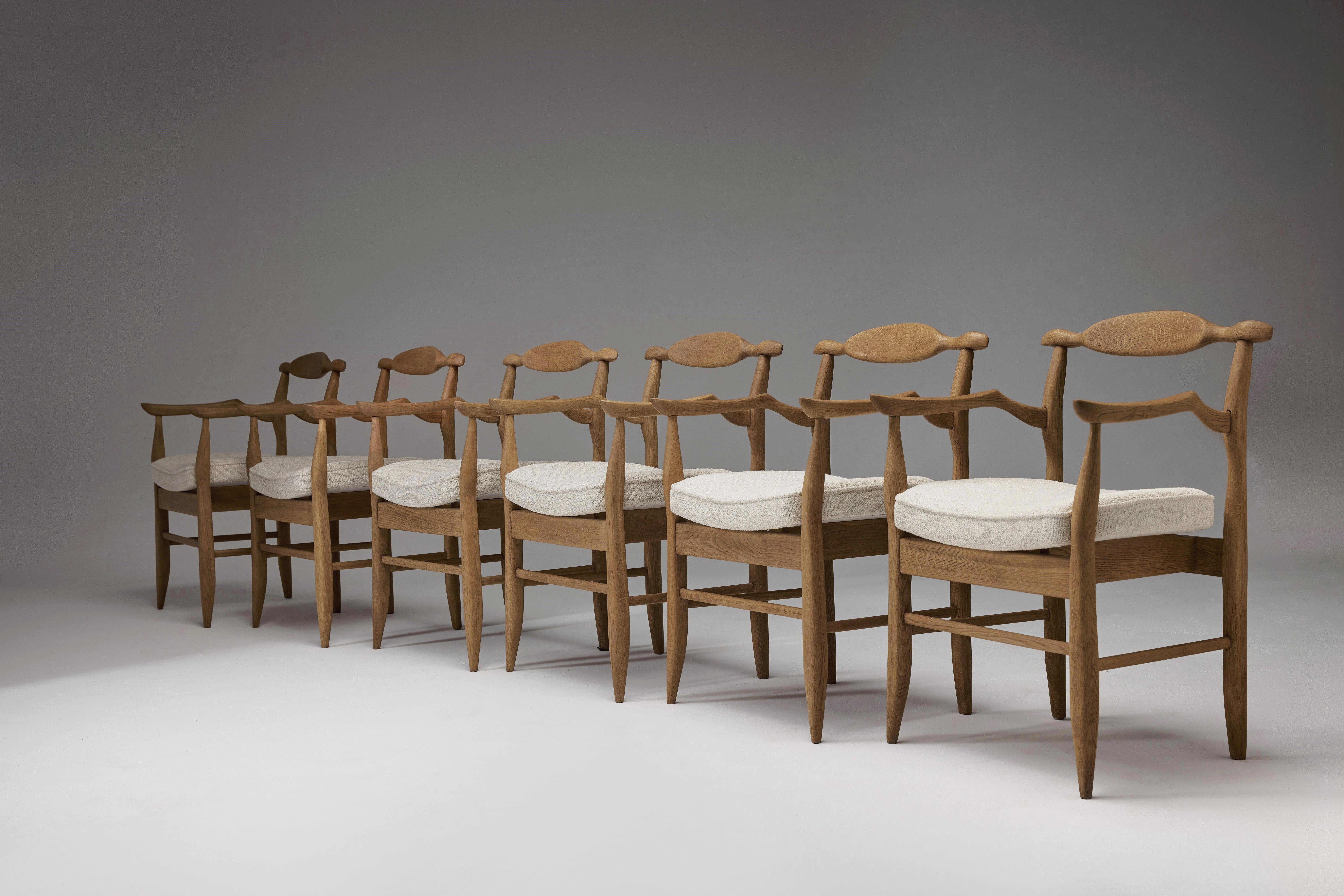 Set of eight consisting of very rare pair of 'Fumay' chairs with upholstered rest, and six standard 'Fumay' armchairs designed in 1965 by the world-famous French duo, Robert Guillerme and Jacques Chambron. 

 This solid oak “Fumay” set of dinning