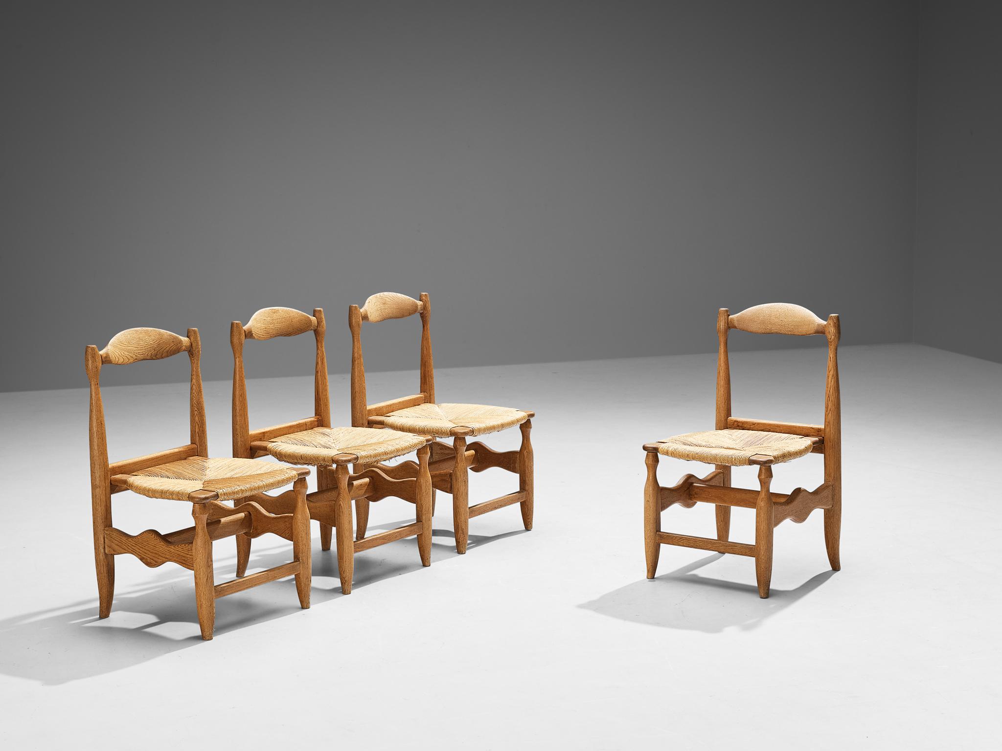 Guillerme et Chambron pour Votre Maison, ensemble de quatre chaises de salle à manger modèle 'Charlotte', chêne, paille, France, années 1960.

Ensemble de quatre chaises de salle à manger rustiques mais élégantes en chêne massif par Guillerme &