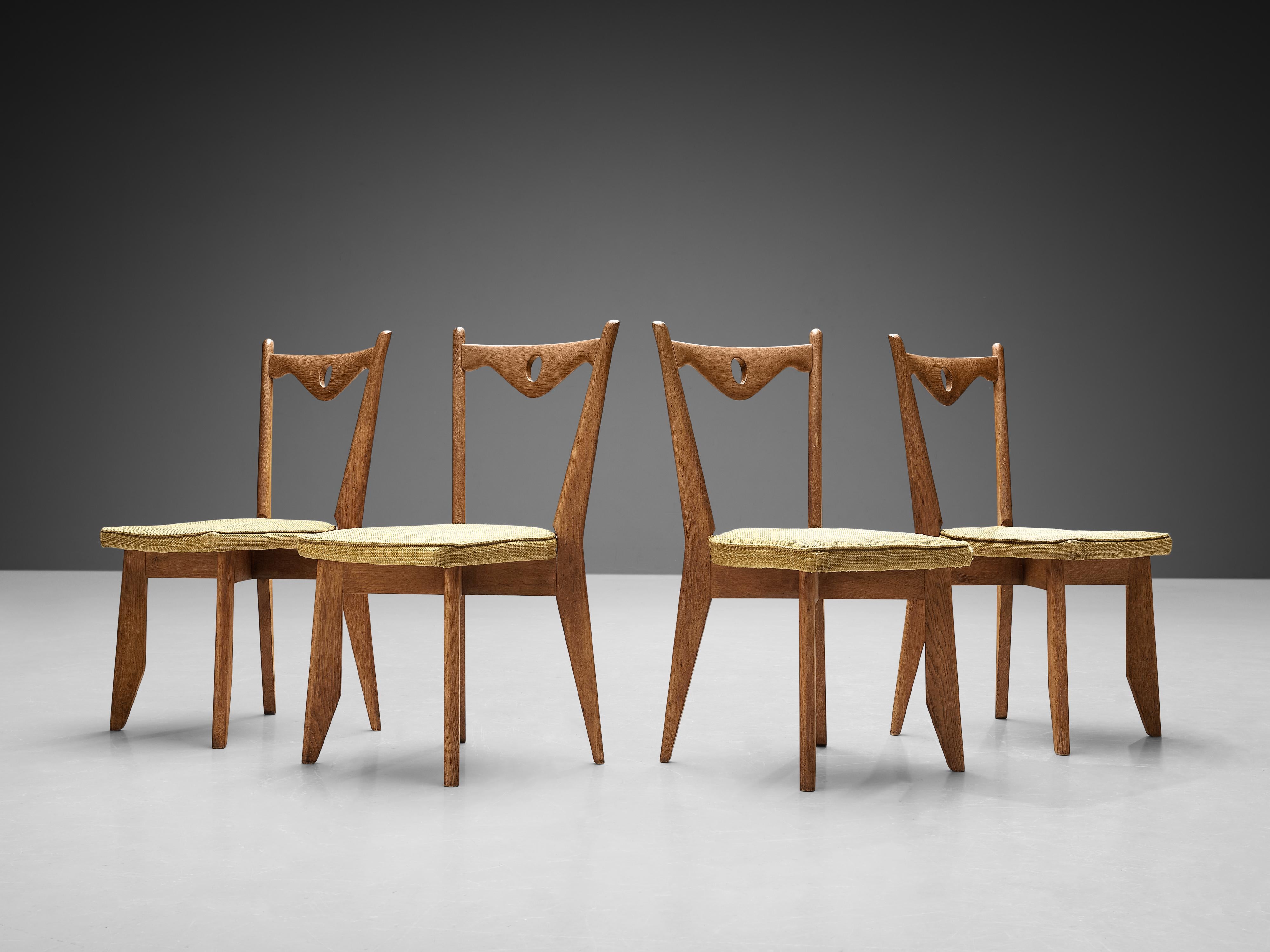 Guillerme et Chambron for Votre Maison, set of four 'Thibault' dining chairs, oak, wool, France, 1960s.

These chairs have characteristic frames with tapered legs and a sculptural back with a scalloped backrest finished with a hole in the middle.