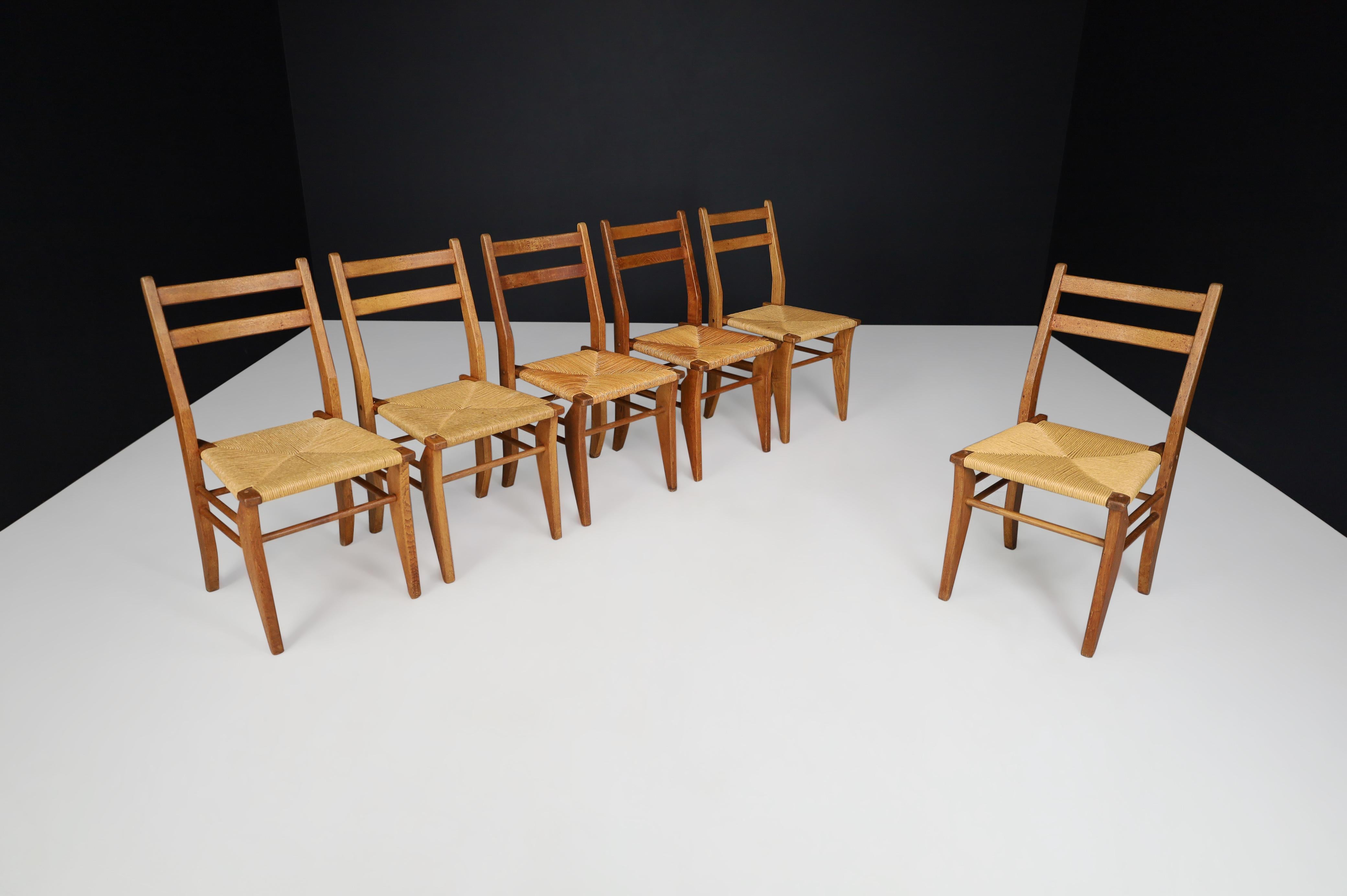 Guillerme & Chambron, set of six dining chairs in oak and rush France, 1960s. 

Set of six dining chairs in solid oak and rush by Guillerme and Chambron. These chairs show a good backrest combined with the typical sculpted legs of the French