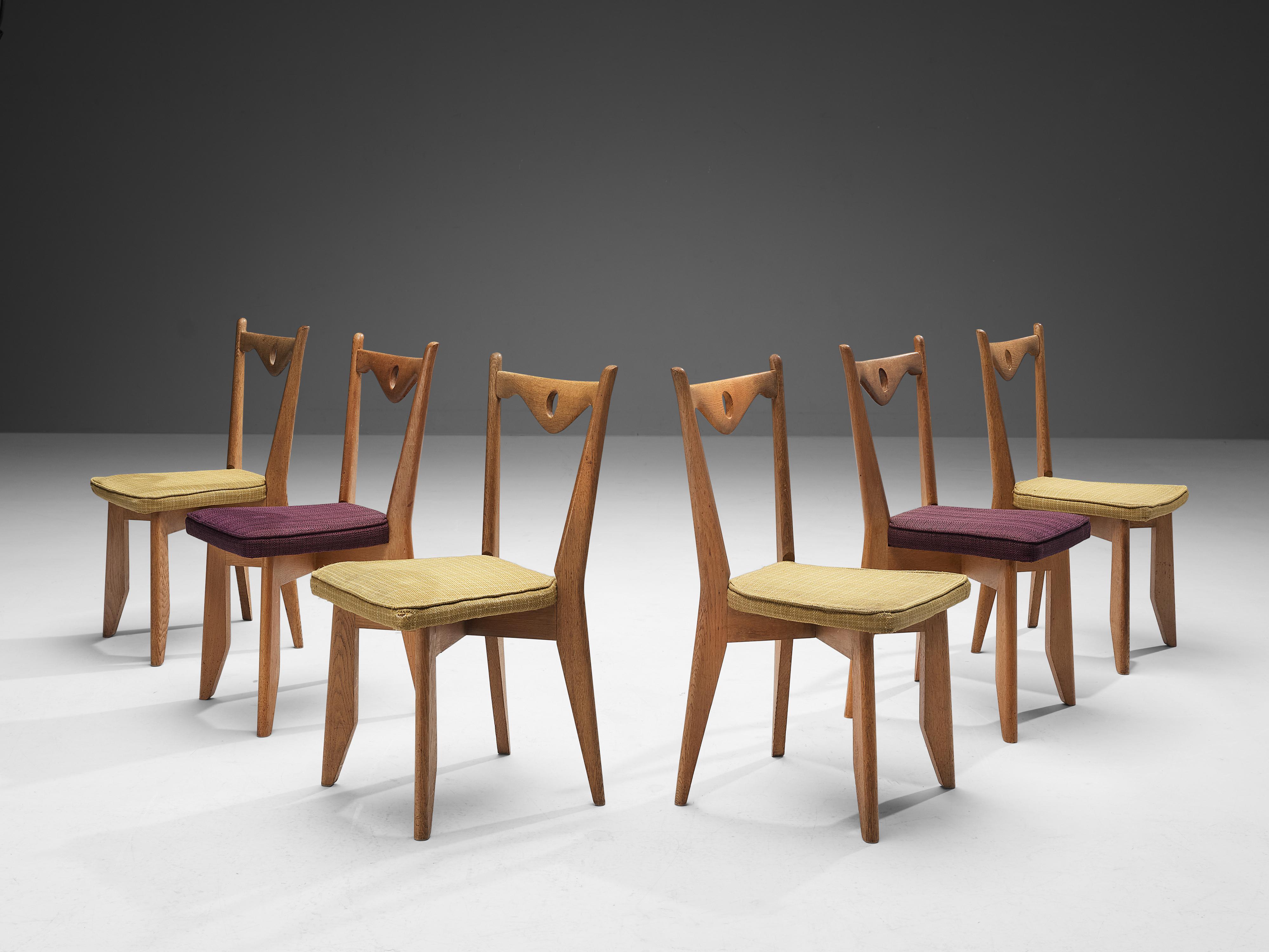 Guillerme et Chambron for Votre Maison, set of six dining chairs, oak, fabric, France, 1960s.

These chairs have characteristic frames with tapered legs and a sculptural back with a downwards facing peak backrest finished with a hole in the middle.