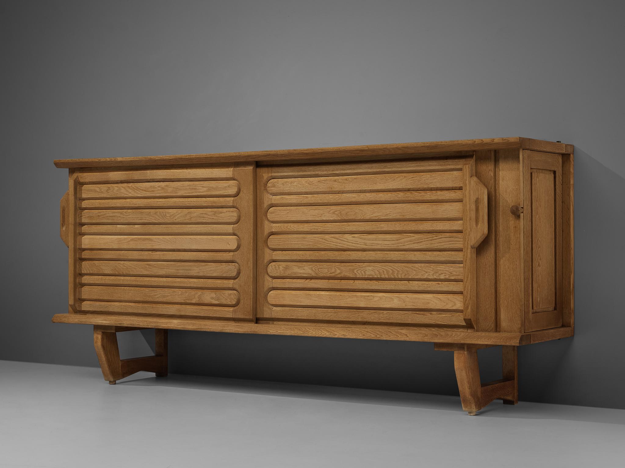 Guillerme & Chambron, sideboard, oak, ceramic, France, 1960s.

Credenza in oak by French designer duo Guillerme & Chambron. This sideboard is equipped with two sliding-doors with a horizontally focused design. The top is inlayed with colourful