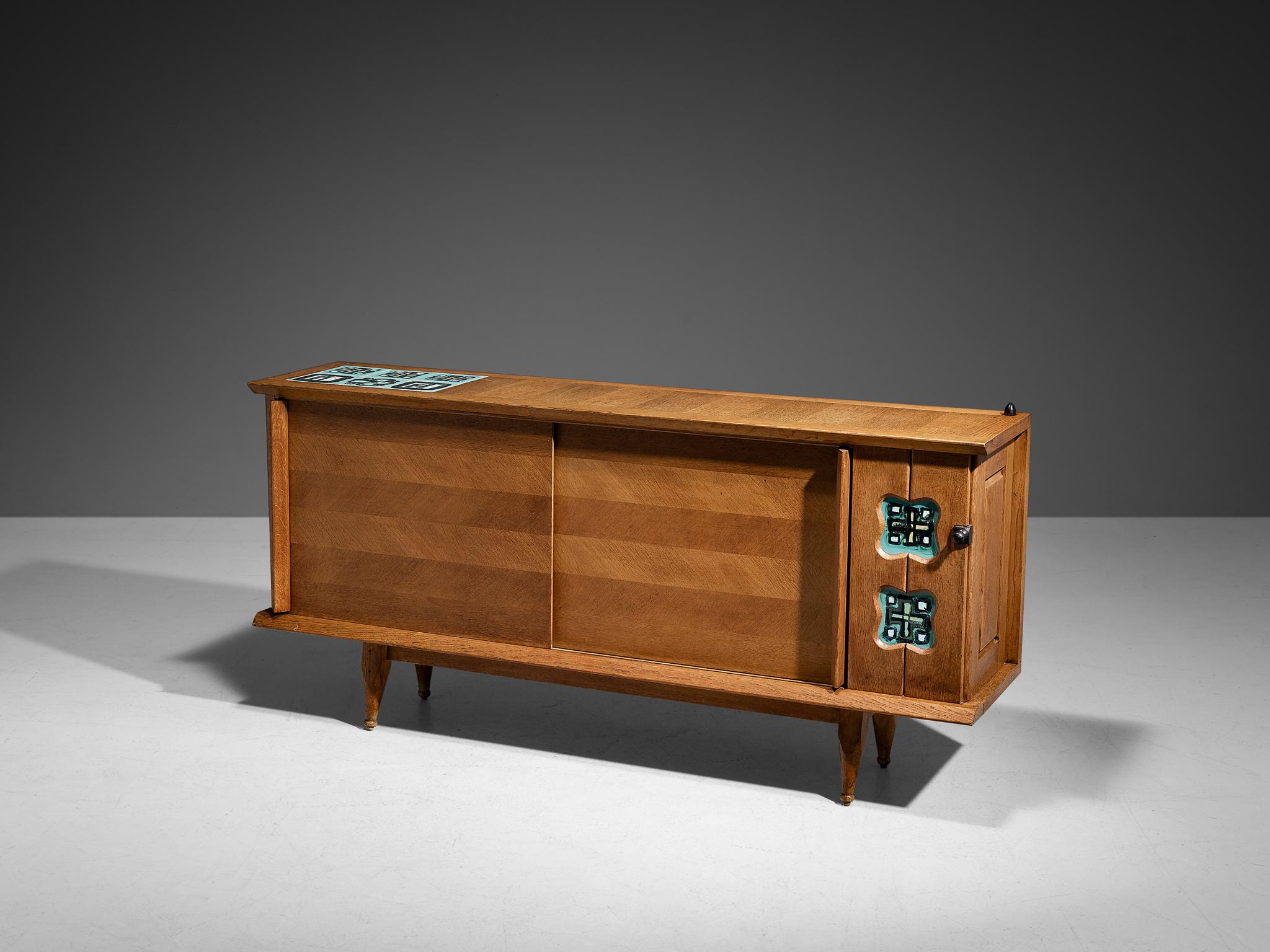 Guillerme et Chambron for Votre Maison, sideboard, oak, oak veneer, ceramic tiles, France, 1960s

This sideboard holds all the characteristics of the French designer duo Jacques Chambron and Robert Guillerme. The front has two sliding doors executed