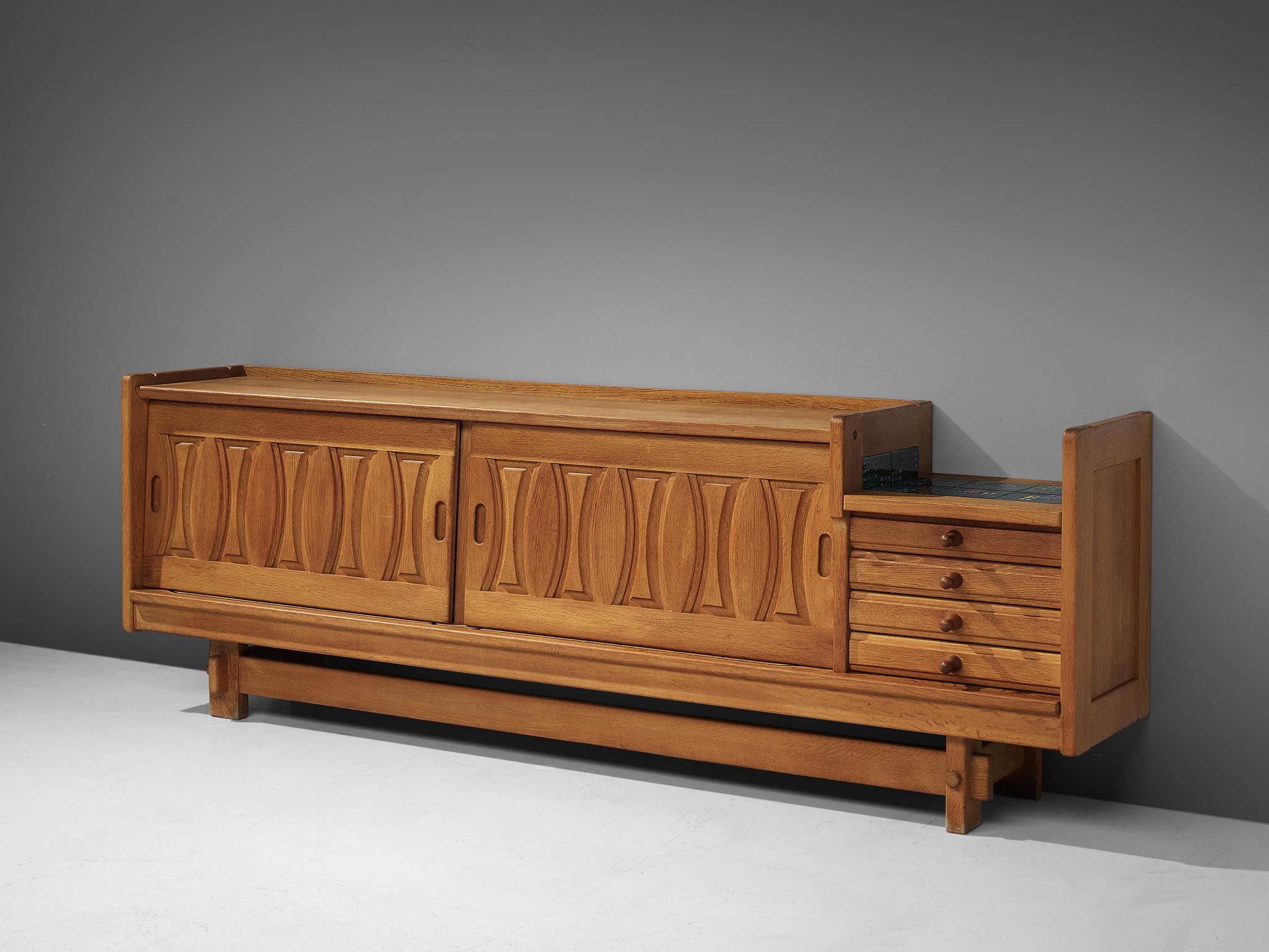 Guillerme et Chambron for Votre Maison, sideboard, oak, ceramics, France, 1960s

Credenza in oak by French designers Guillerme & Chambron. This sideboard is equipped with two sliding doors and a set of drawers. The front of the sideboard is
