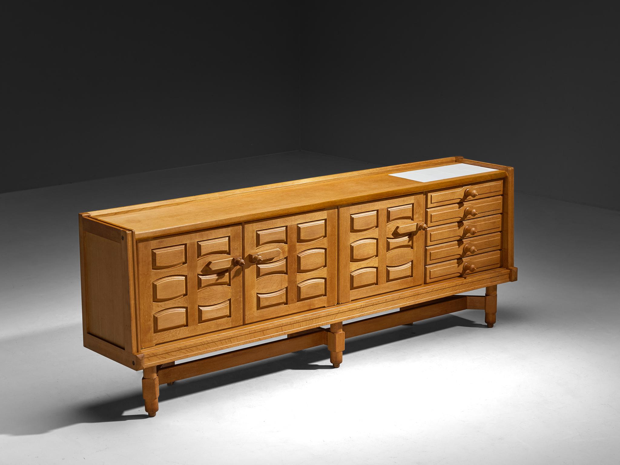 Guillerme et Chambron pour Votre Maison, buffet, chêne massif, céramique, France, années 1960

Ce charmant buffet, conçu par le talentueux duo de designers Guillerme et Chambron, se distingue par sa construction solide, ses lignes sculptées exquises