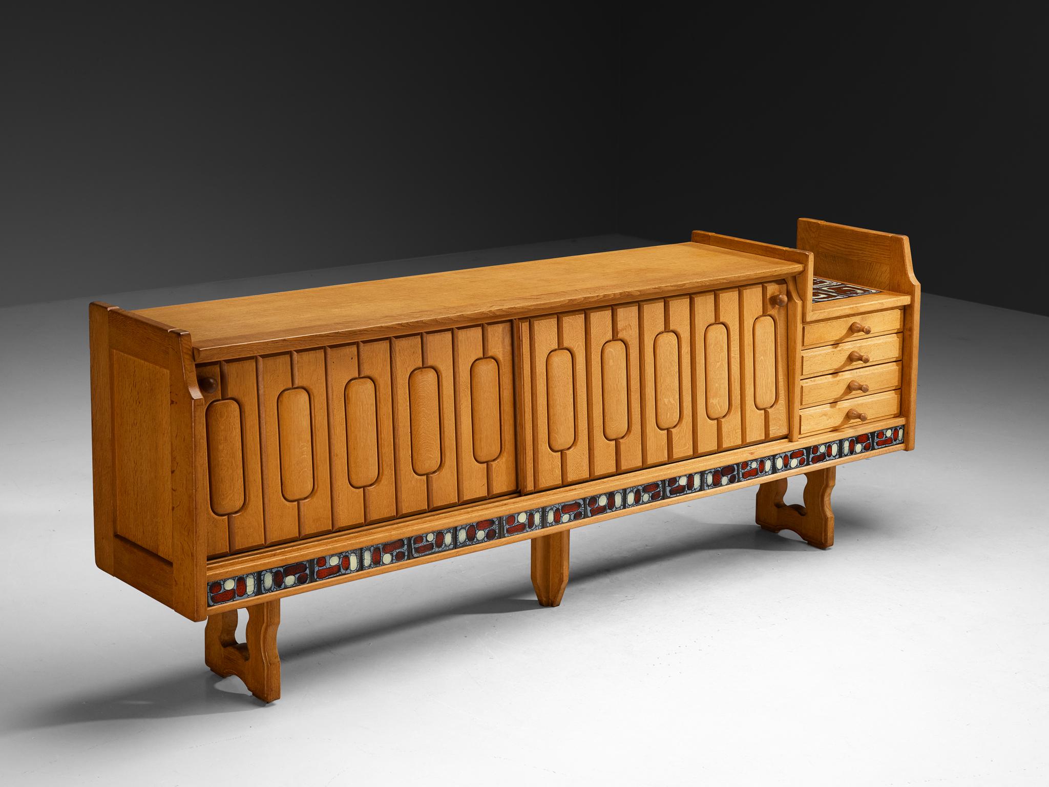 Guillerme et Chambron for Votre Maison, 'Simon' sideboard, oak, ceramic, France, 1960s

The Simon credenza in oak, designed by the French duo Guillerme & Chambron, offers a confident and joyful statement in mid-century modern design. At once