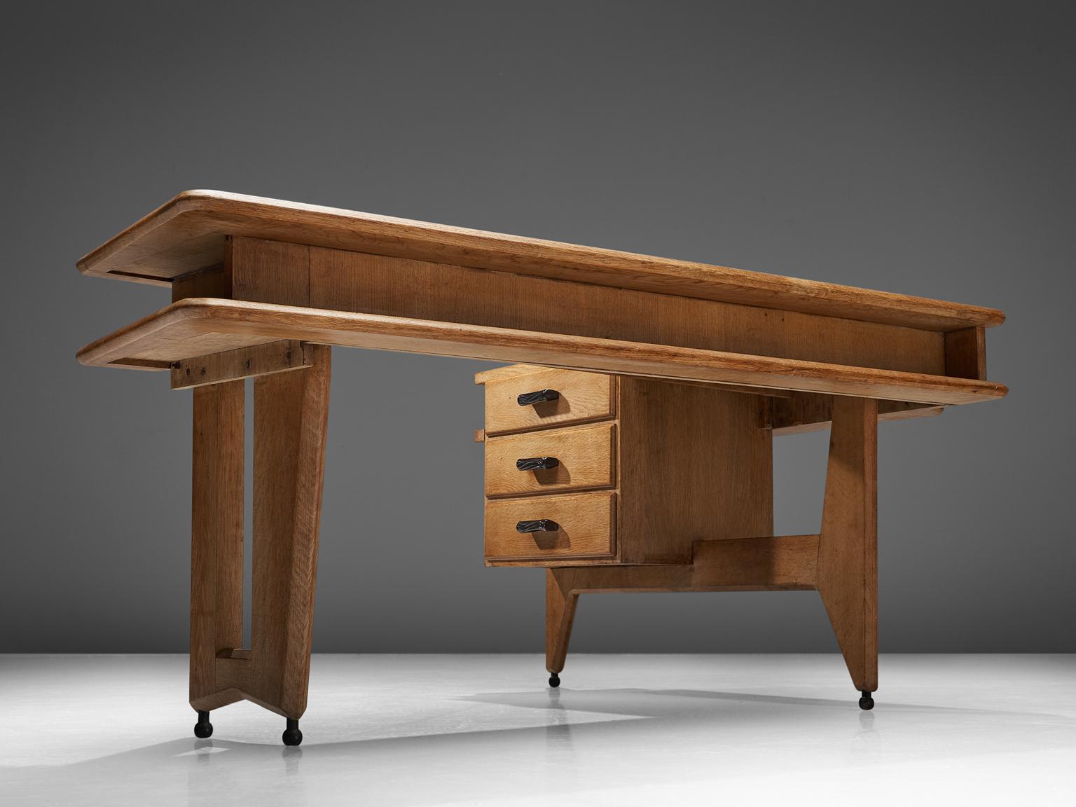 Guillerme & Chambron, desk in oak, France, 1960s.

This desk and return, is executed in solid oak by French designers Guillerme et Chambron. This elegant corner desk shows interesting details. First there is the shaped of the top, which is