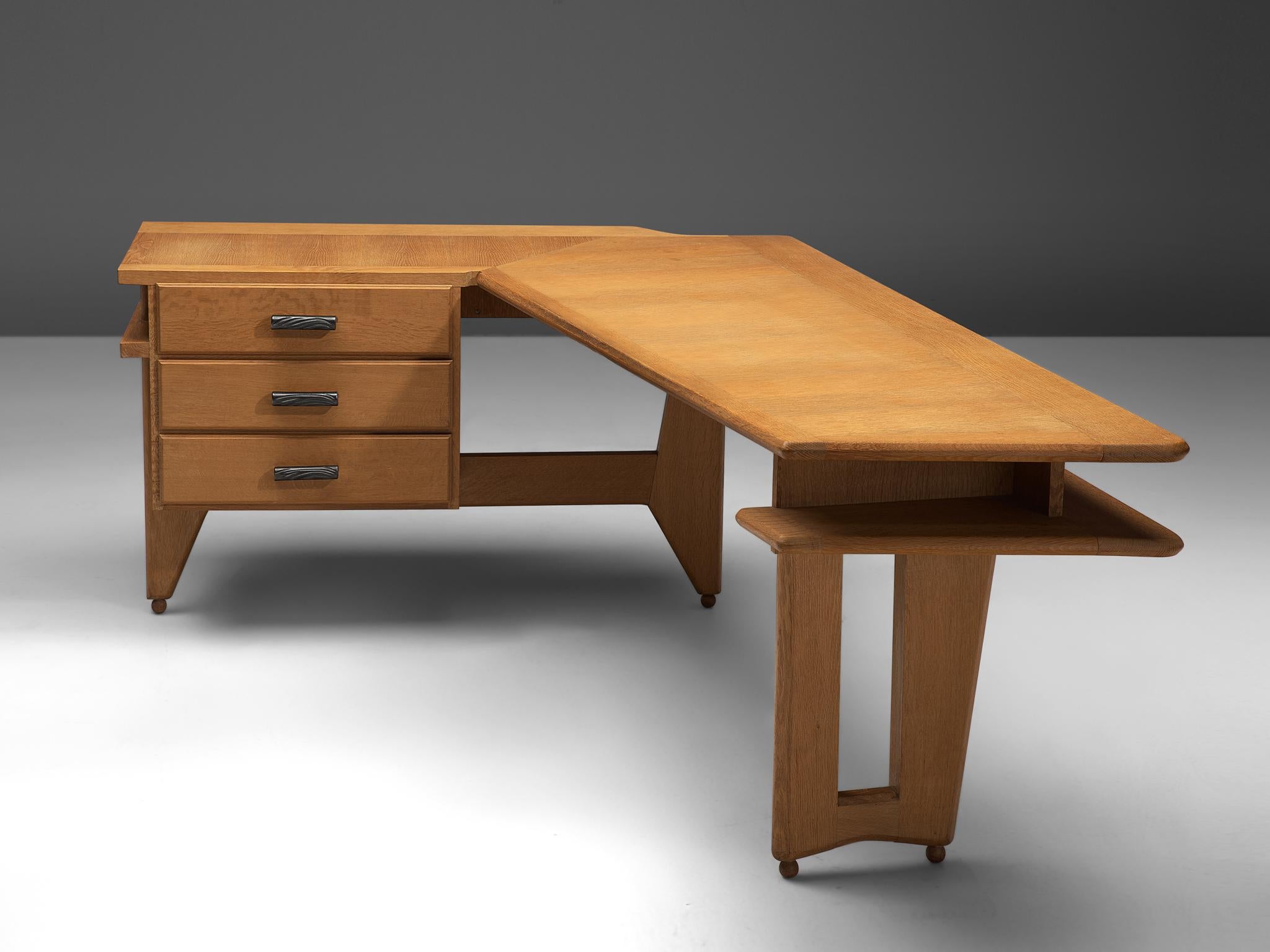 Guillerme & Chambron, desk in oak, France, 1960s.

This desk and return, is executed in solid oak by French designers Guillerme et Chambron. This elegant corner desk shows interesting details. First there is the shaped of the top, which is L-shaped.