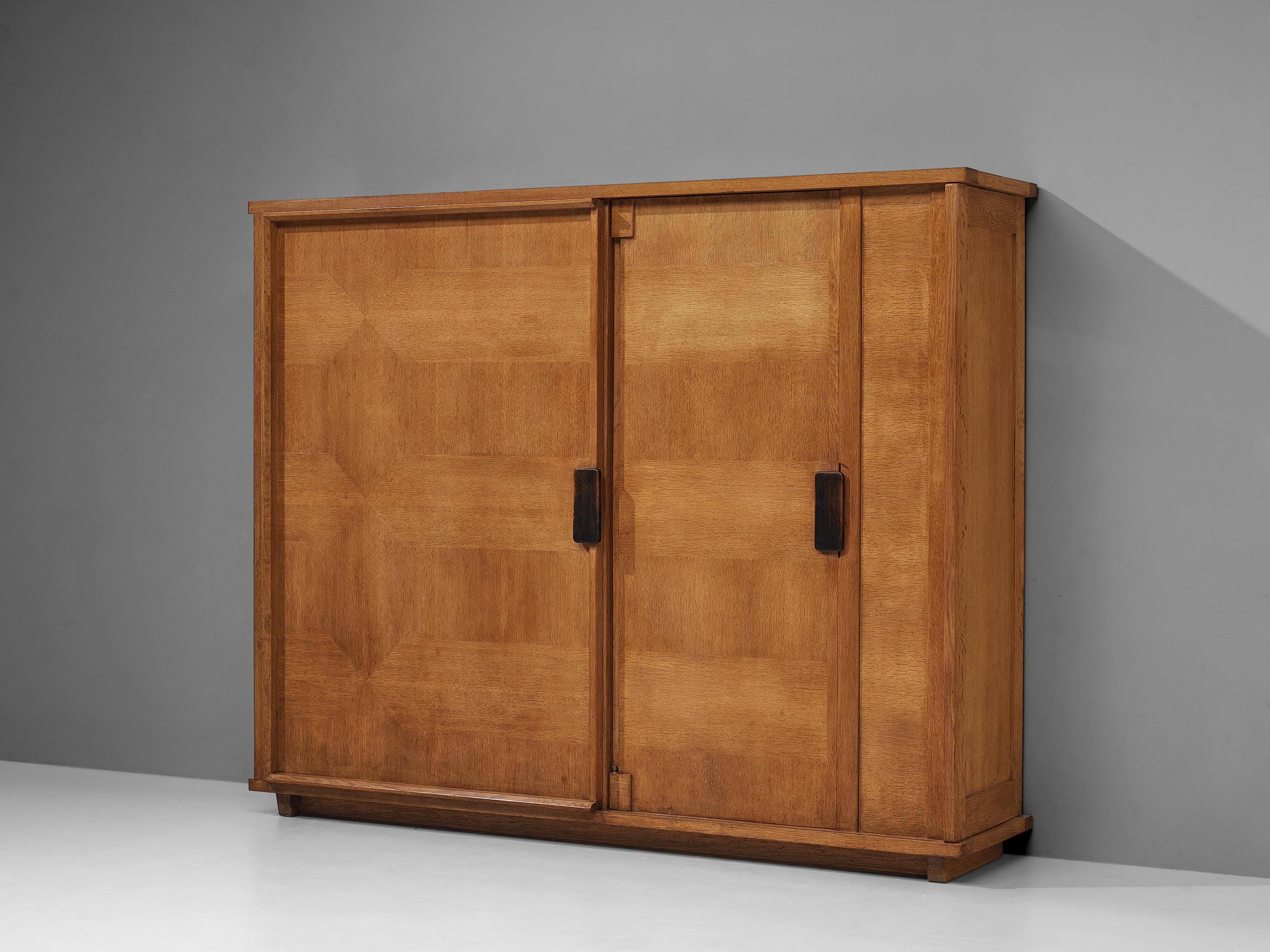 Guillerme et Chambron for Votre Maison, wardrobe, oak, France, 1960s

This grand wardrobe in blond oak wood has versatile (hidden) storage facilities. Two doors in different size structure the front. Both door panels are equipped with black handles