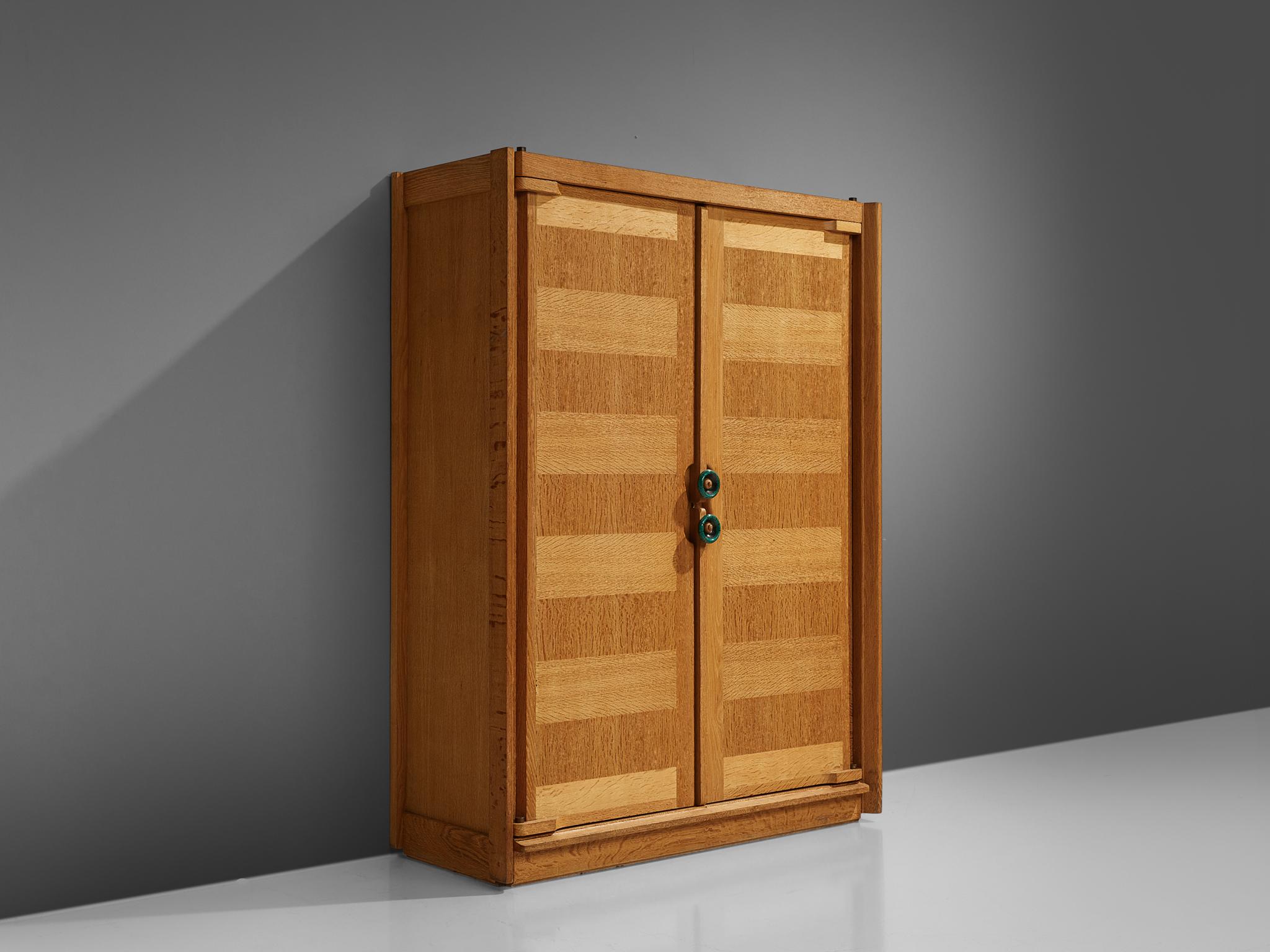 Guillerme et Chambron, armoire, oak, France, 1960s.

This case piece is designed by Guillerme and Chambron and features geometric oak inlays, which is characteristic for the French duo. The armoire is equipped with colorful, ceramic handles. The