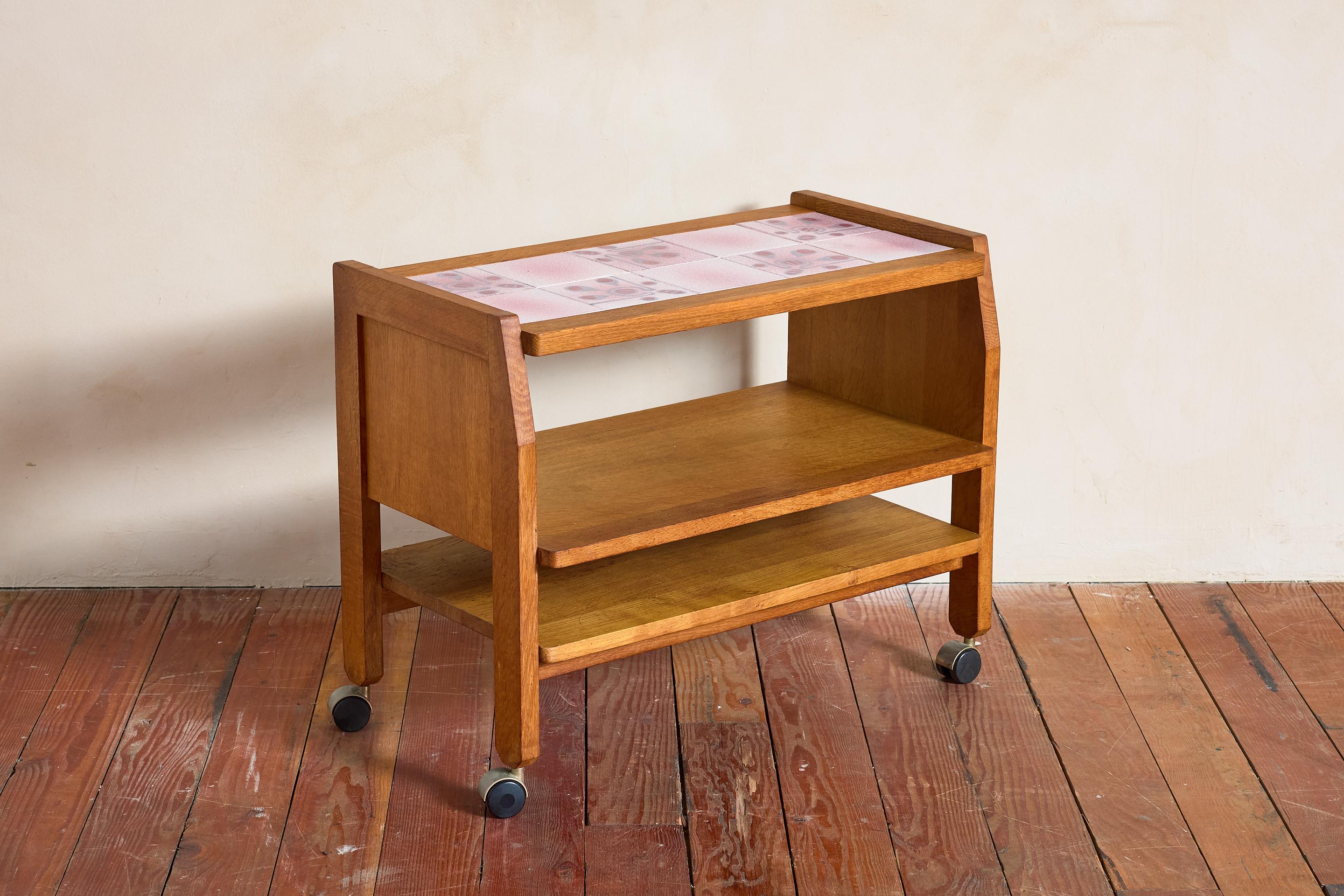 Guillerme et Chambron rolling trolly / bar cart, France 1950's

Oak frame with two shelves and original pink ceramic tile tops 

Wonderful patina / great piece! 