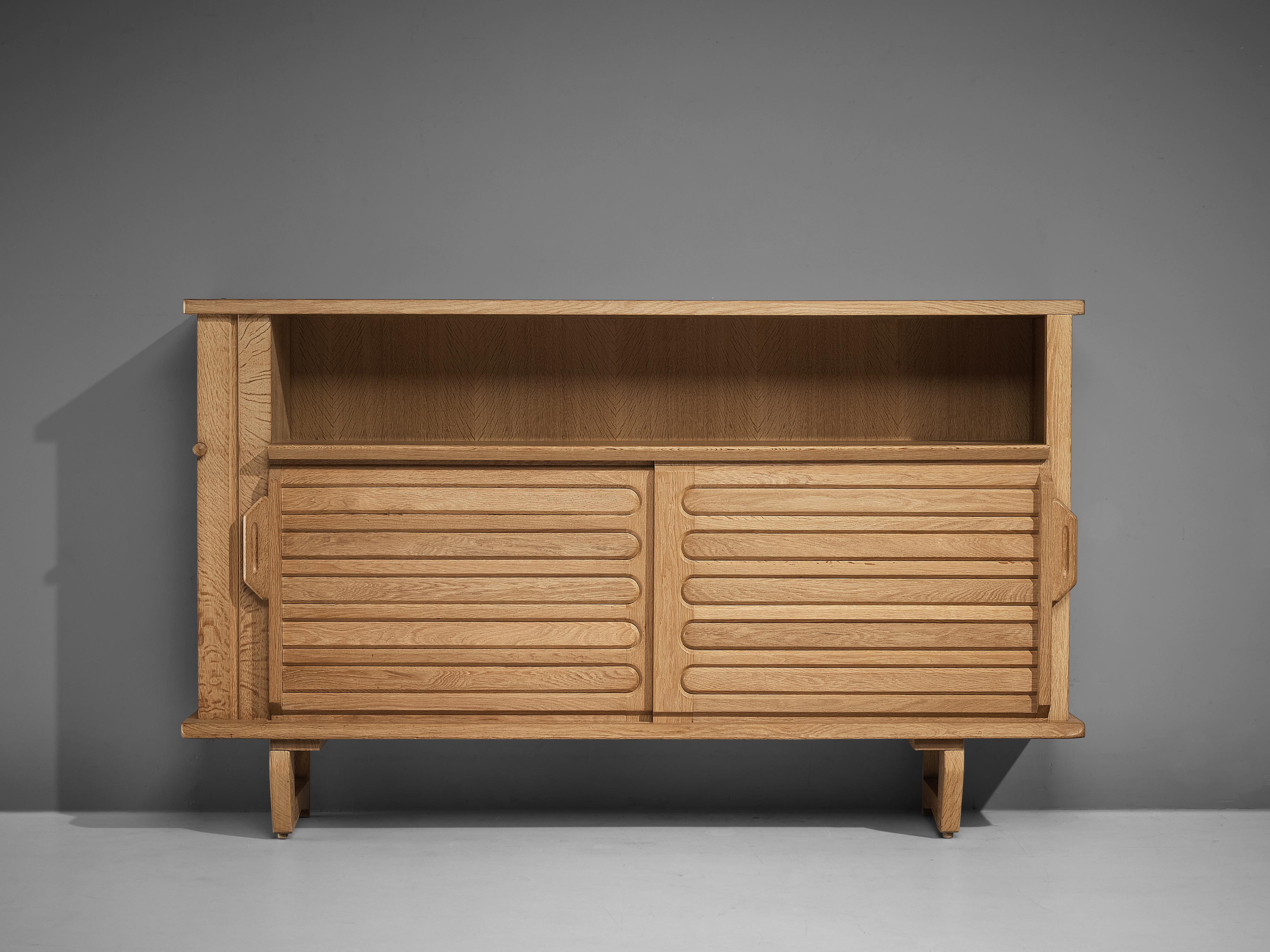 Guillerme et Chambron for Votre Maison, high board, oak, France, 1950s 

This sculptural cabinet is designed by the designer duo Guillerme and Chambron. The piece is executed in solid oak and consists of two large storage compartments, one open