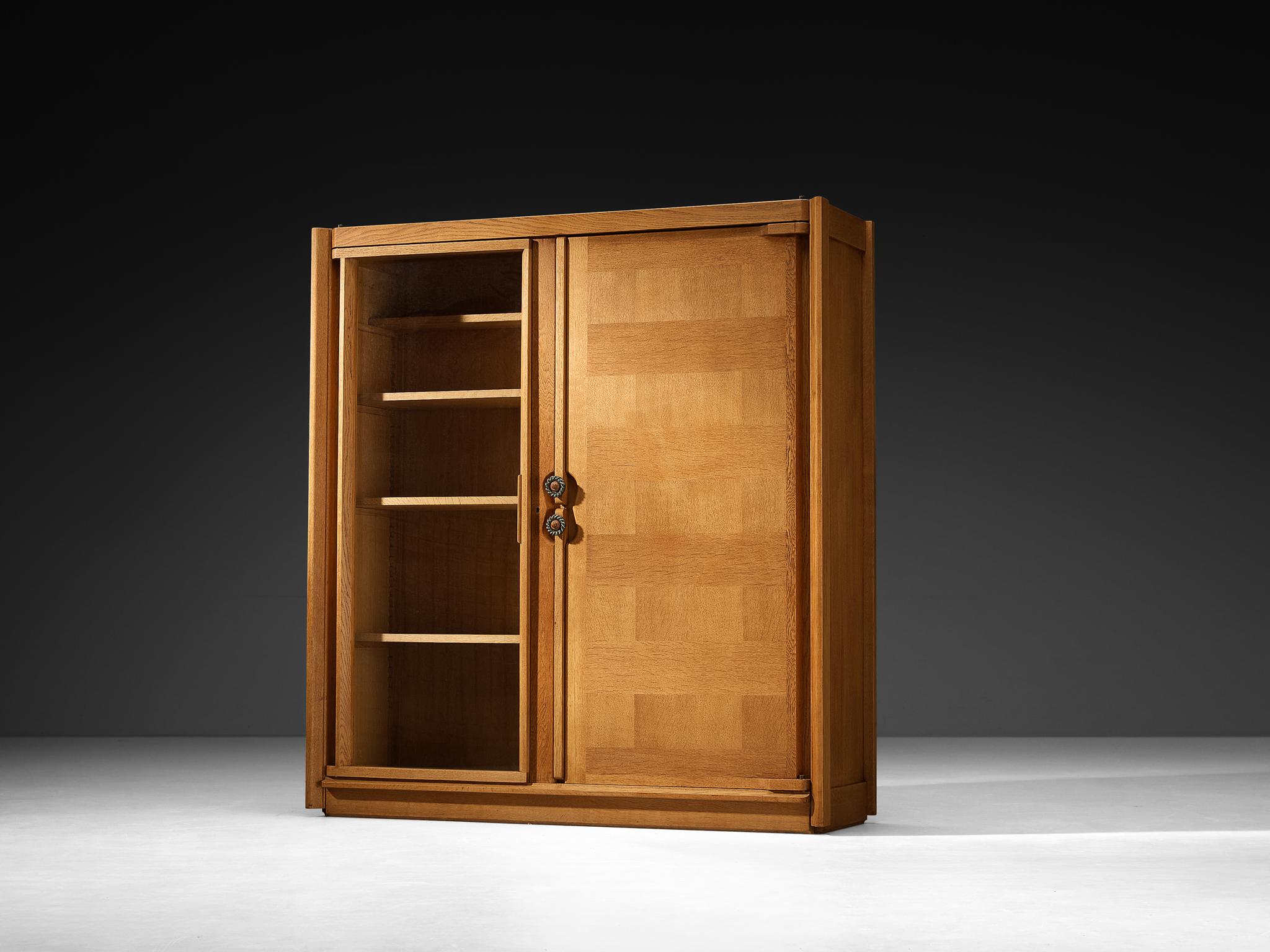 Guillerme et Chambron, armoire, chêne, verre, céramique, France, années 1960

Cette pièce est conçue par Guillerme et Chambron et présente des incrustations géométriques en chêne qui créent des panneaux horizontaux sur la façade du meuble. Ce motif