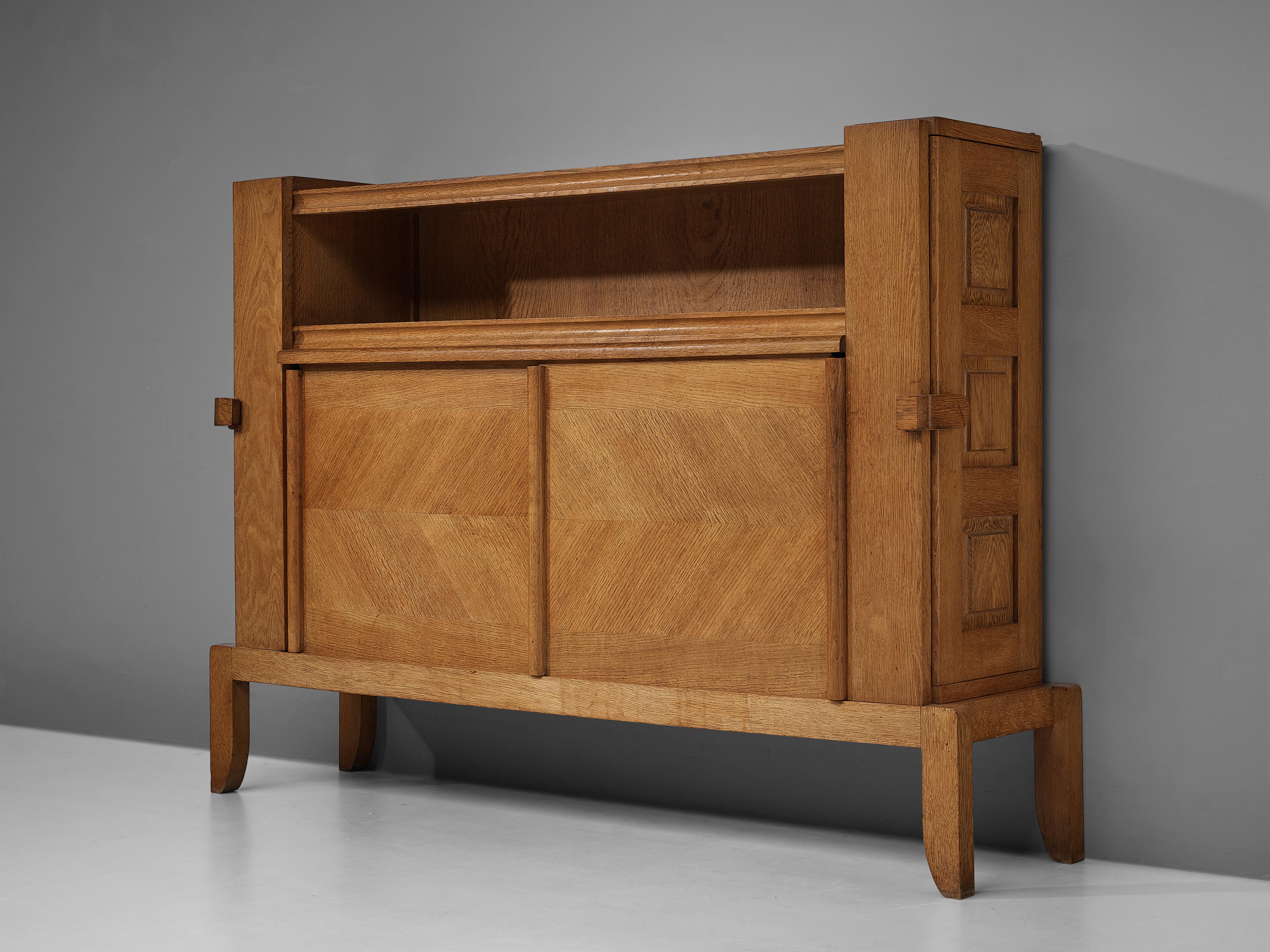 Guillerme et Chambron for Votre Maison, cabinet, oak, France, 1970s.

This case piece is designed by Guillerme et Chambron and features a decorative design in the doors and legs. The cabinet offers plenty of storage, with several shelves and