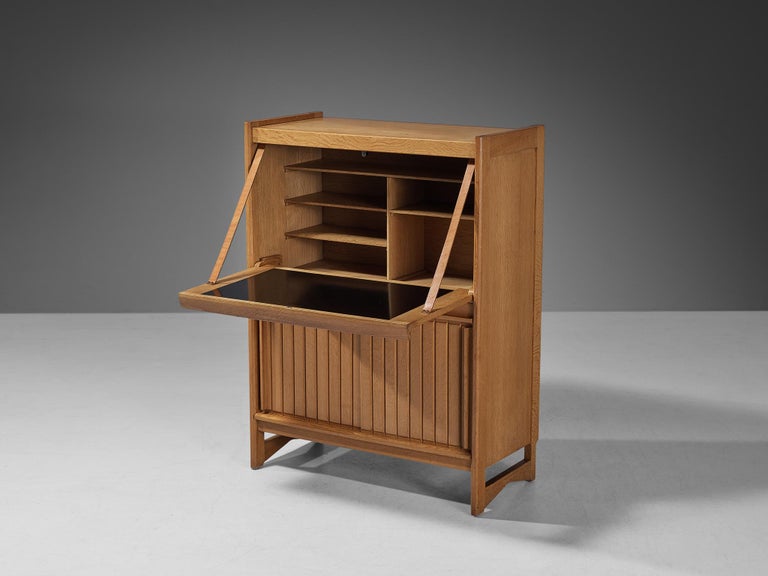 Guillerme et Chambron for Votre Maison, cabinet, oak, melamine, brass, leather, France, 1960s 

This multifunctional cabinet is based on a well-designed structure where aesthetics and functionally come hand in hand. The front holds the