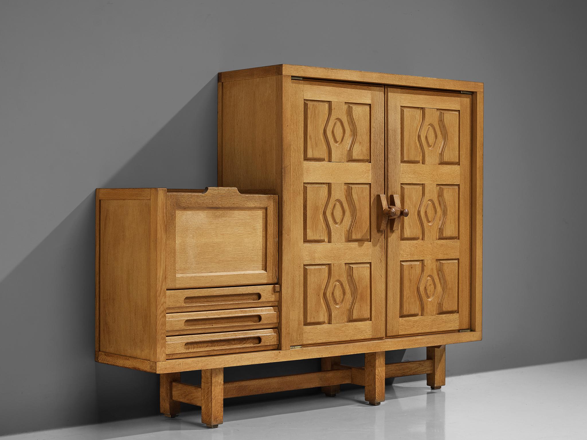 Guillerme and Chambron, cabinet, model 'Thierry', oak, France, 1960s.

This model 'Thierry' case piece is designed by Guillerme and Chambron. It features geometric engravings in the doors of the high part, with sculptural handles. On the inside, it
