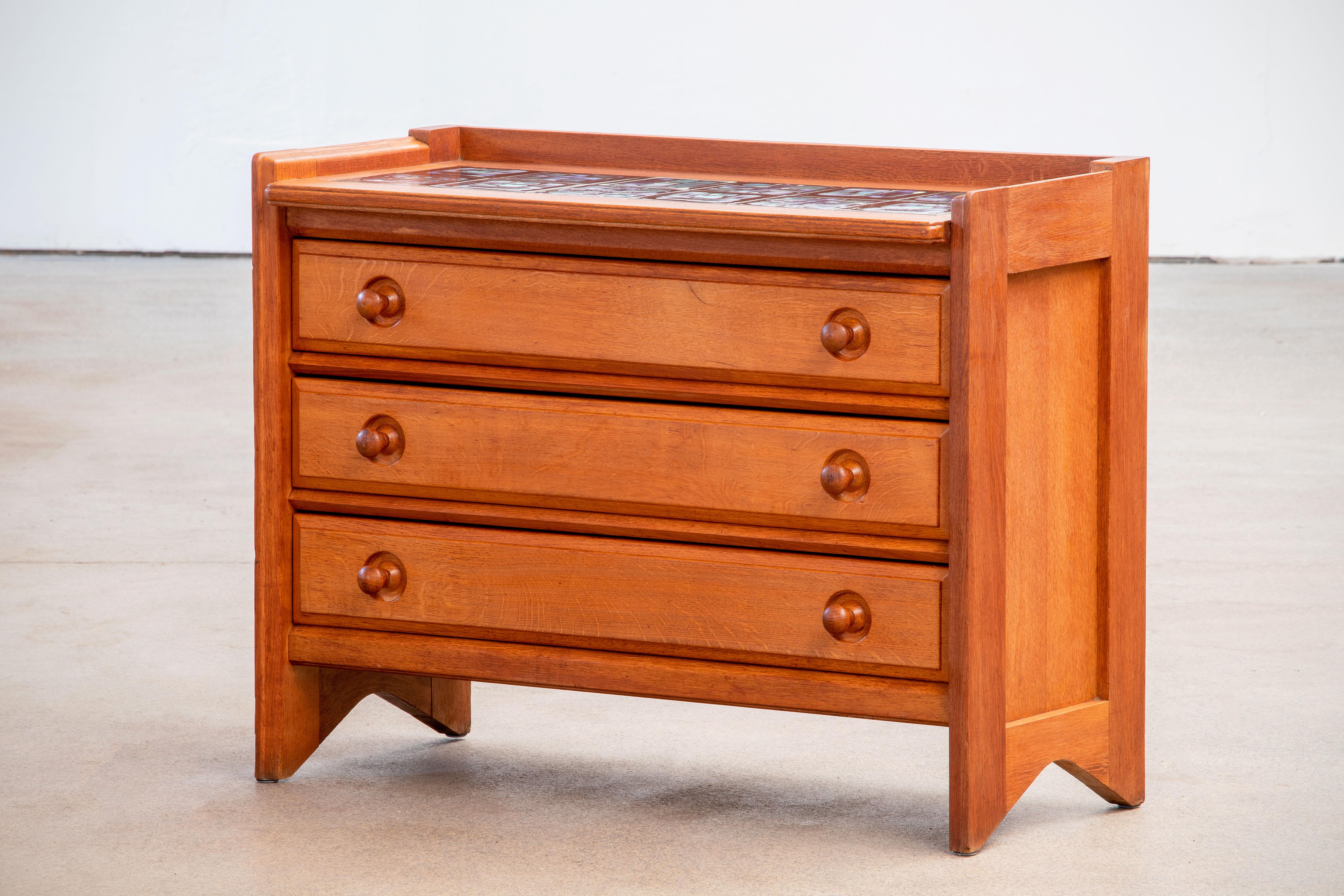 Elegant and rare chest of drawers by French designers Guillerme and Chambron in oak with ceramic top. Chest of 4 drawers In overall good vintage condition.
   