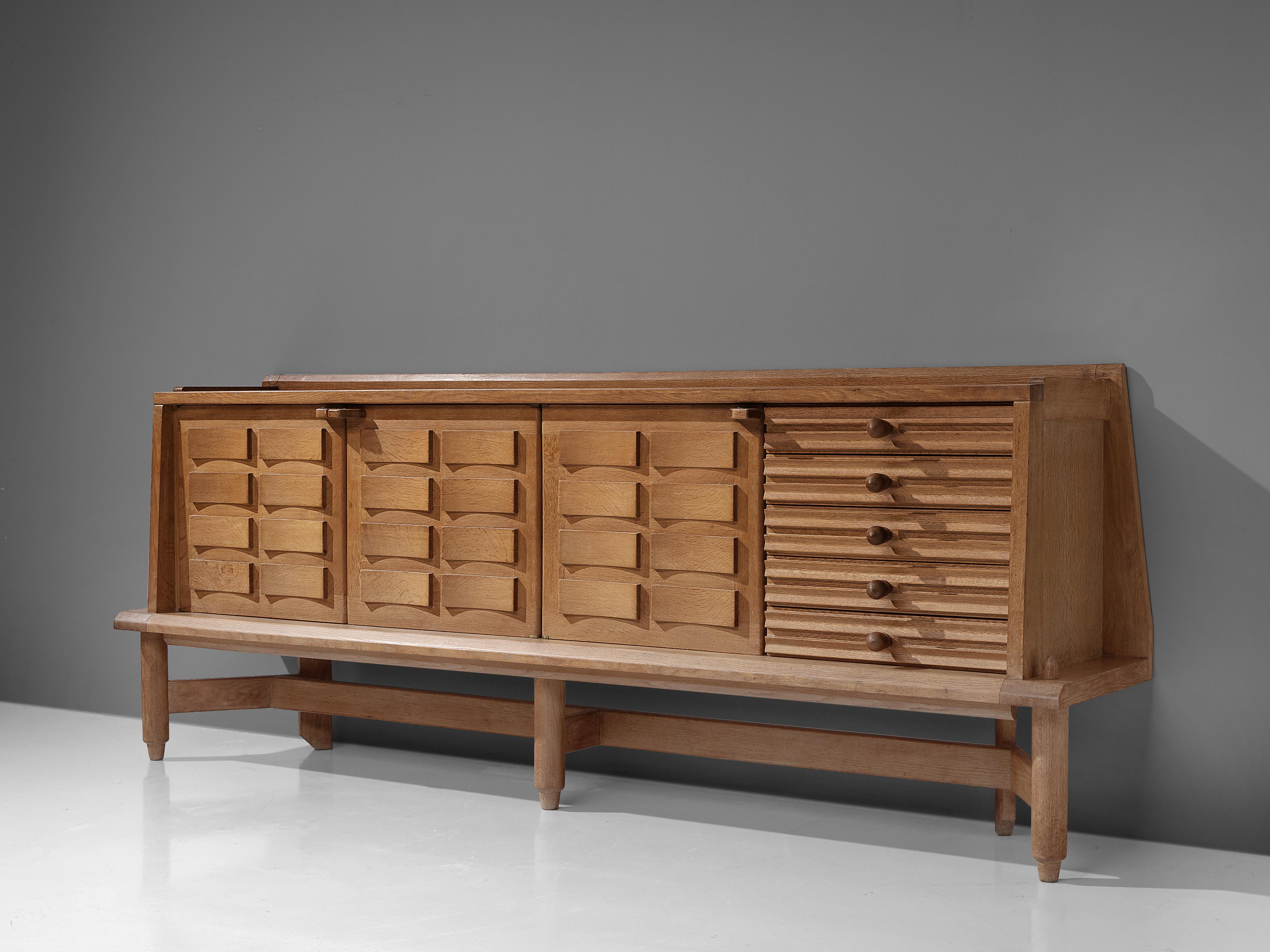 Guillerme and Chambron, large sideboard, oak, ceramic, France, 1960s.

This large sideboard is designed by Guillerme and Chambron and features a geometric structure on the three doors in the front. Behind these doors you'll find plenty of storage