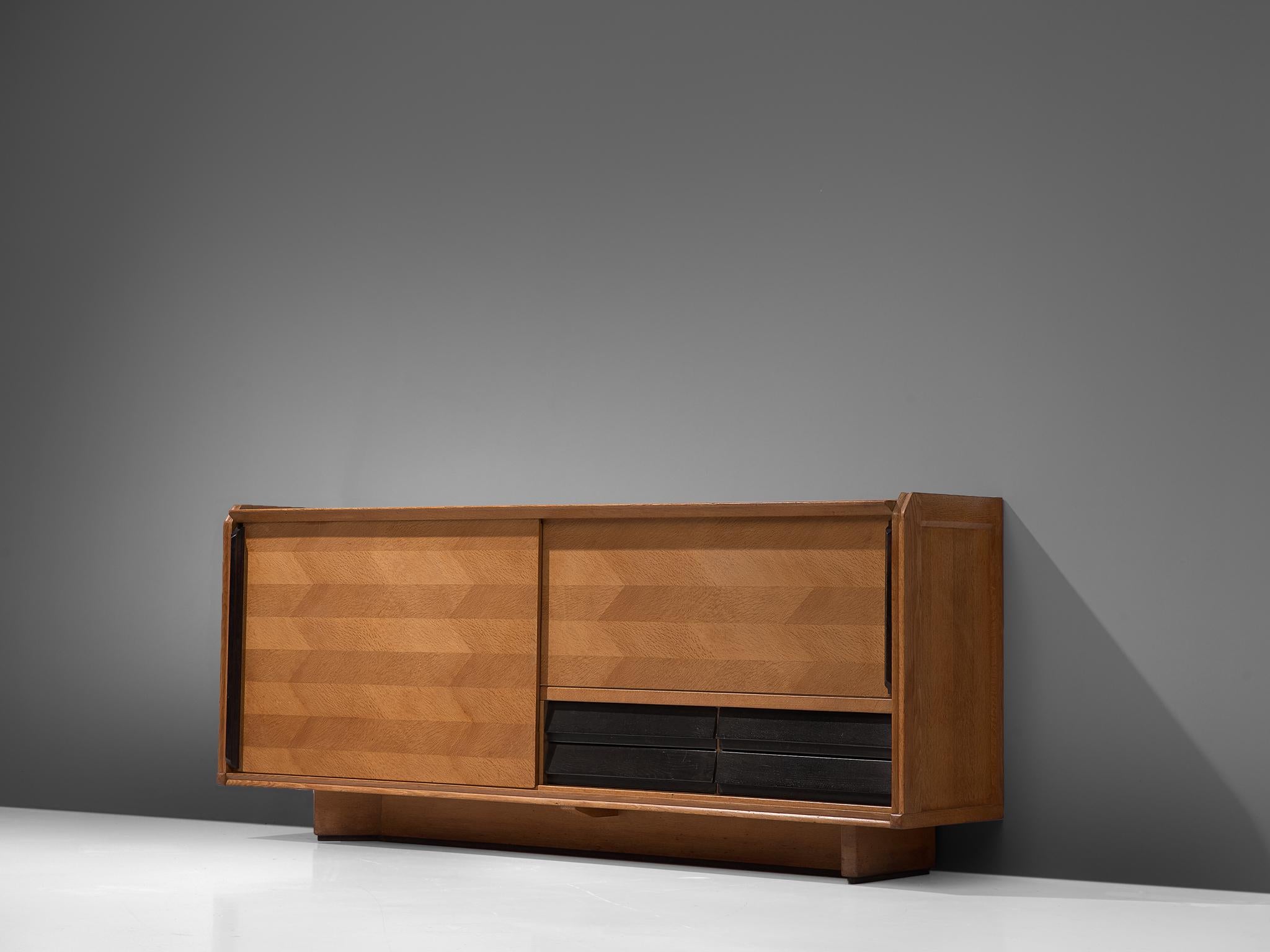 Guillerme et Chambron for Votre Maison, credenza, oak, France, 1960s.

Elegant sideboard designed by the French designer duo Guillerme and Chambron. The sideboard is characterized by the horizontal oakwood inlay patterns. The oak doors feature a