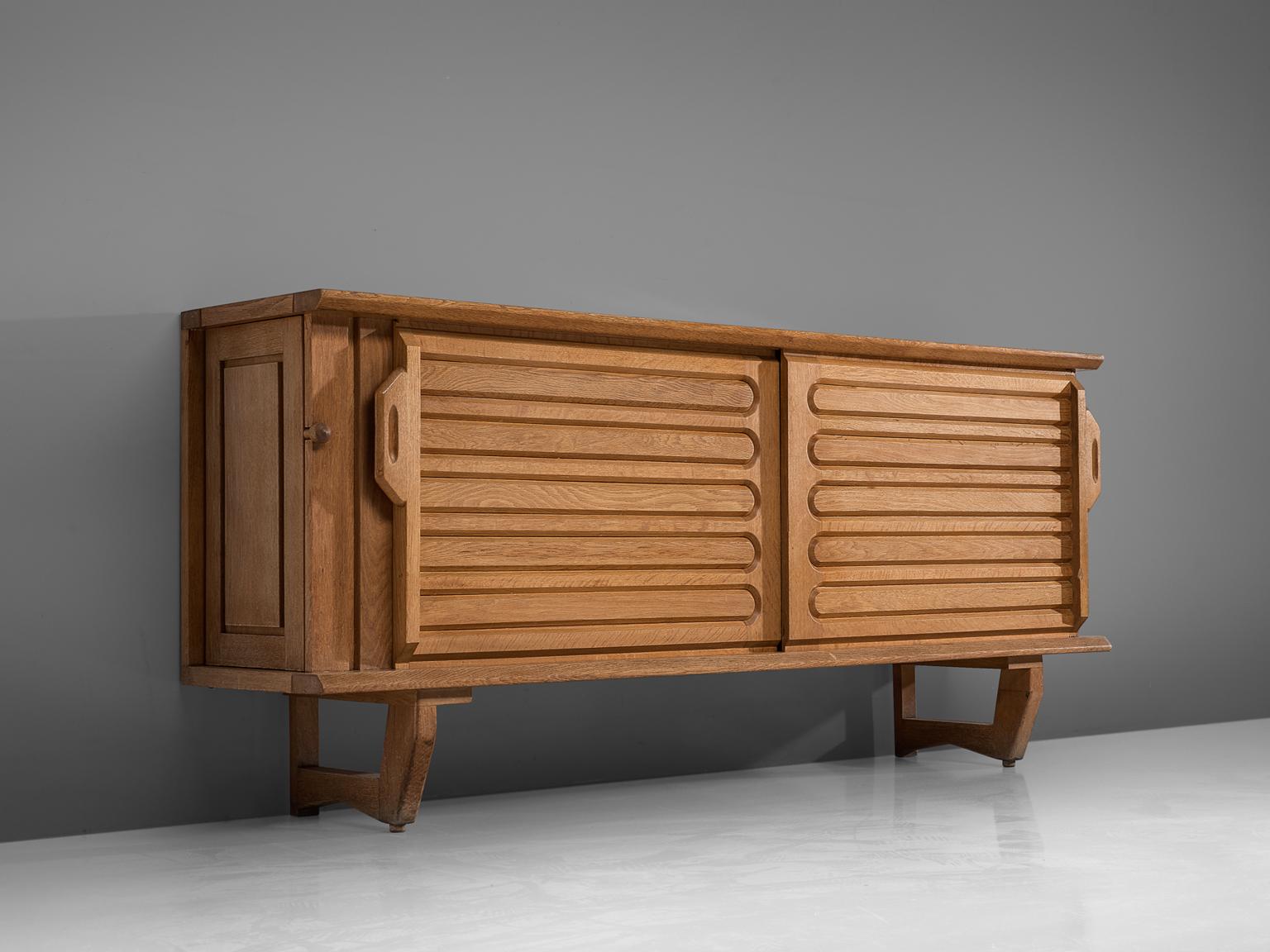 Guillerme et Chambron for Votre Maison, sideboard in oak, France 1960s.

This well proportioned sideboard is designed by Guillerme and Chambron and features horizontal engravings in the front sliding doors. On the sides, the cabinet features two