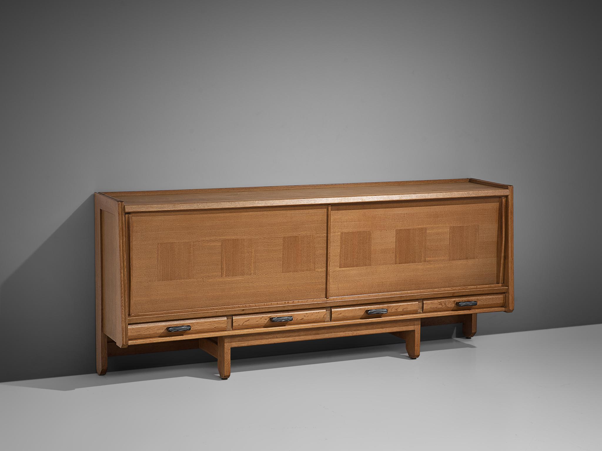 Guillerme et Chambron for Votre Maison, credenza, oak, France, 1960s. 

A sideboard with two sliding doors by French designer duo Guillerme and Chambron. This quite solid cabinet holds beautiful inlaid woodwork. Underneath the sliding doors there