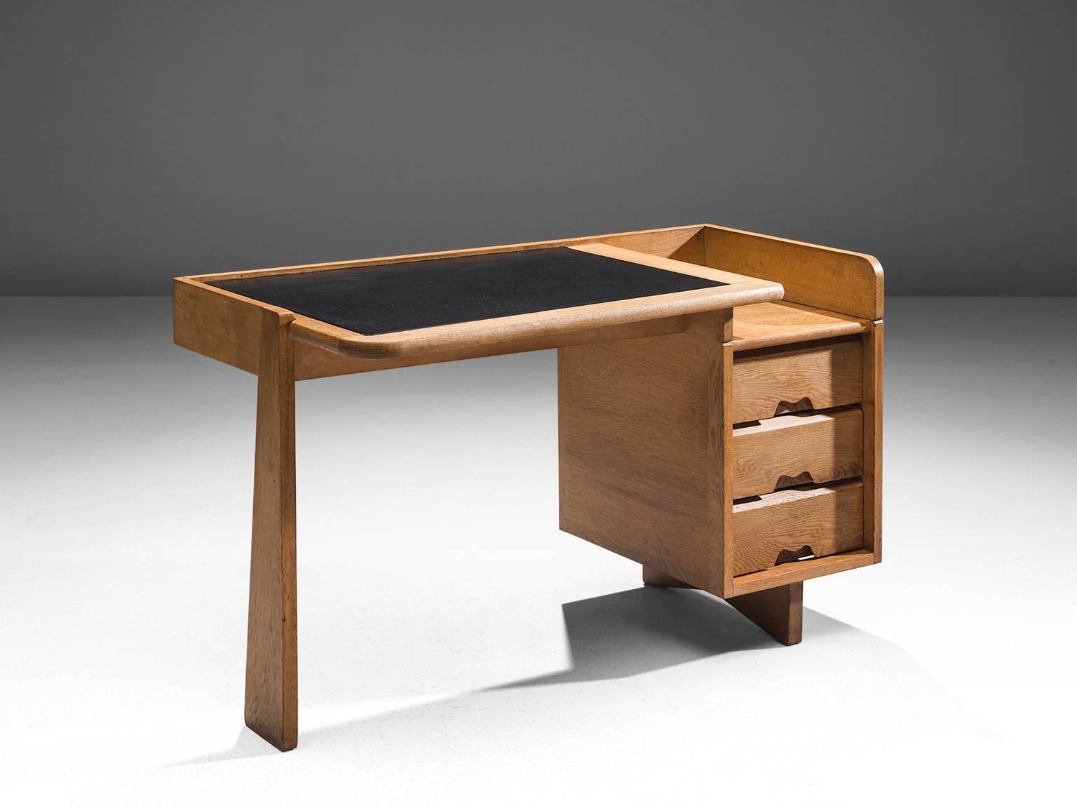 Guillerme et Chambron, desk, oak and black leather, France, 1960s. 

This small desk is designed by the French designer duo Guillerme and Chambron. This writing desk holds the characteristic decorations and lines of this duo such as the decorative