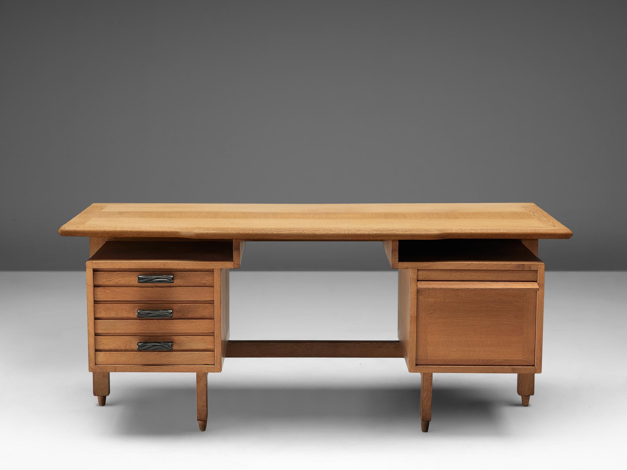 Guillerme et Chambron, desk, oak, France, 1950s.

This desk has a large work surface and are equipped with plenty of storage space due well decorated drawers with ceramic handles on the left and one large compartment on the right to fully enjoy