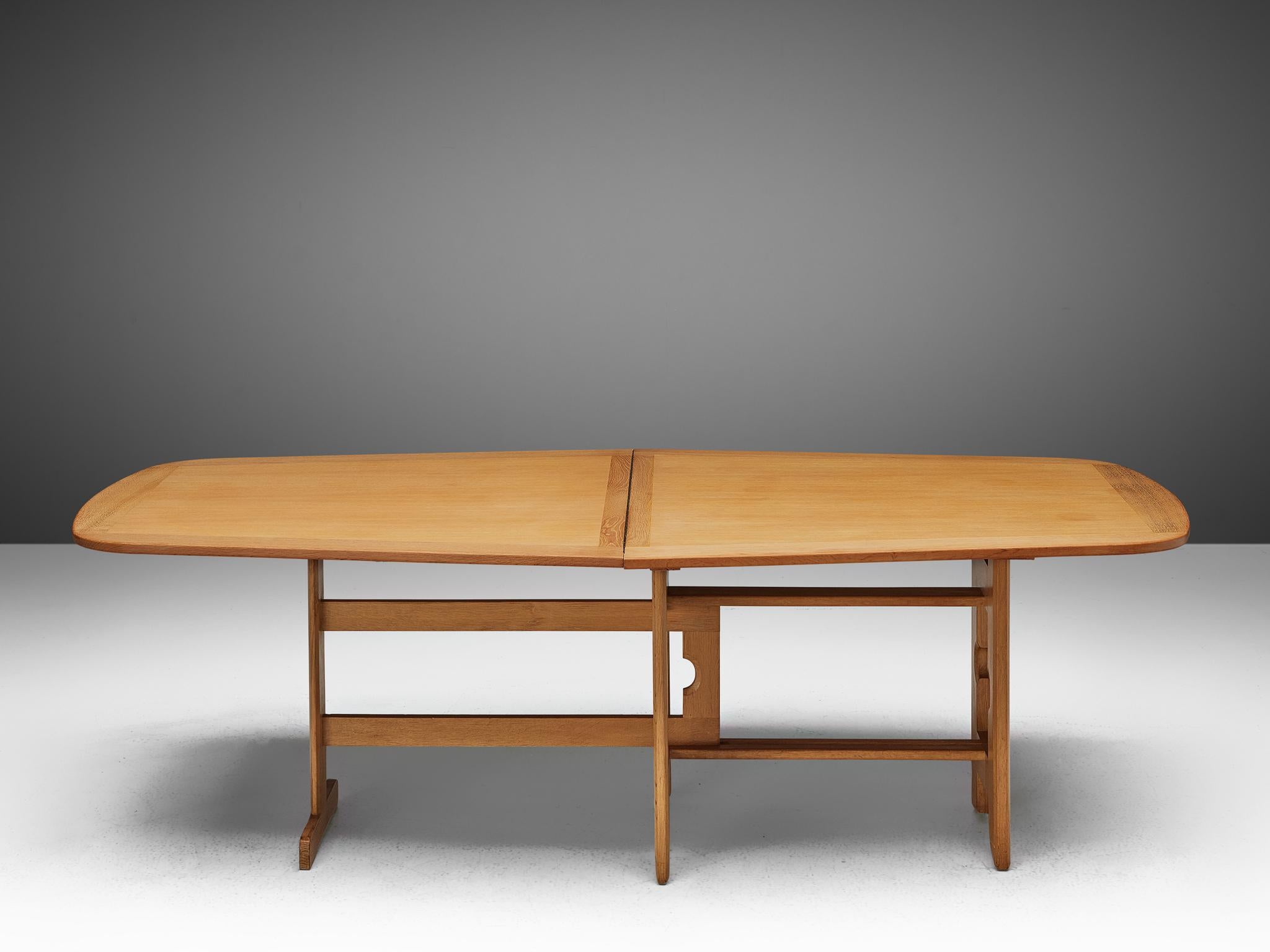 Guillerme et Chambron, extendable dining table, oak, 1960s.

Freeform shaped dining table with inlayed top. This extendable table in solid oak comes with a fold out leaf, which makes it a very versatile item. The sculptural three legged base has