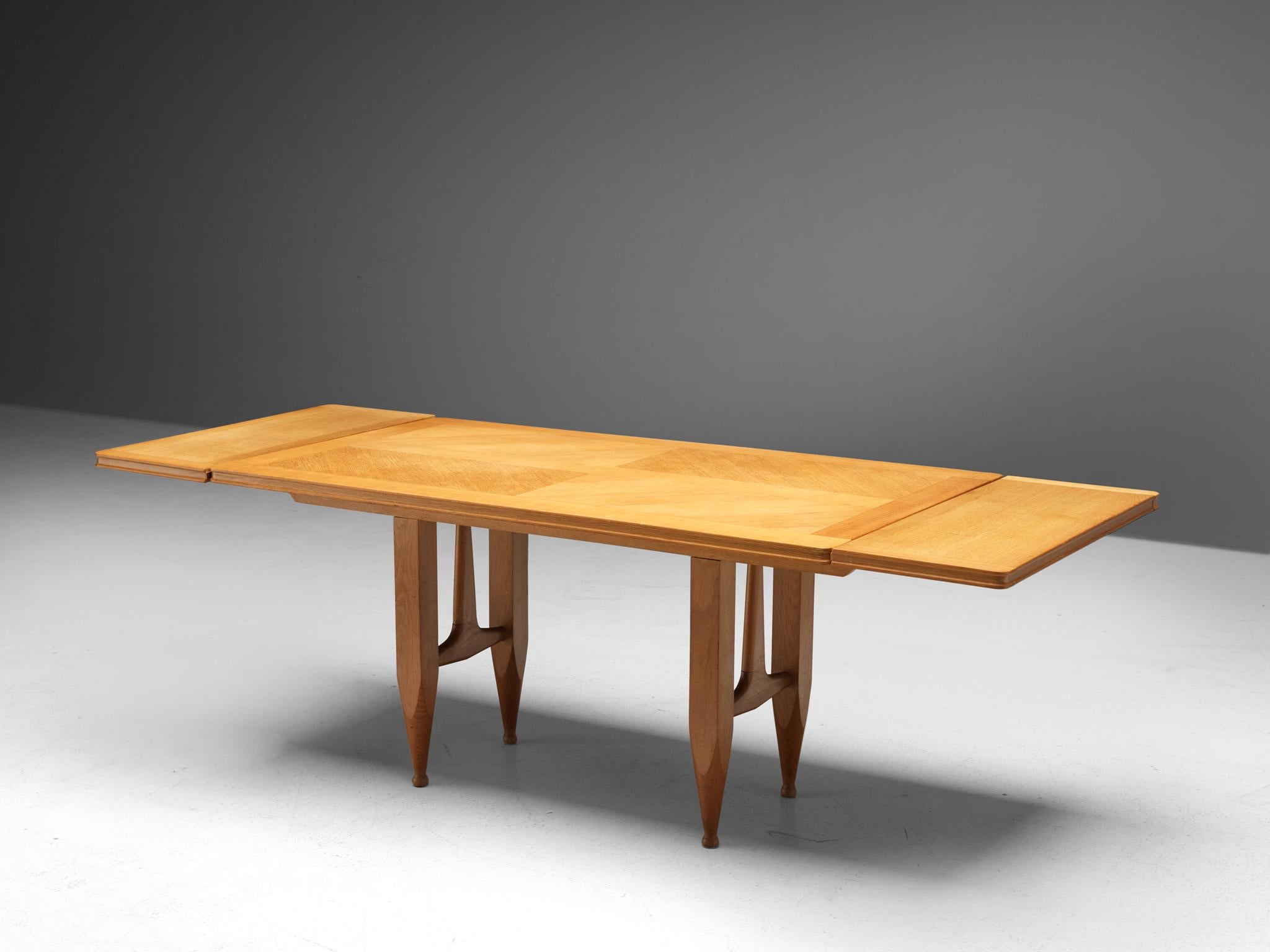 Guillerme et Chambron for Votre Maison, extendable dining table, oak, 1960s.

Oval shaped dining table with inlayed top. This extendable table in solid oak comes with two optional leaves, which makes it a very versatile item. The sculptural two