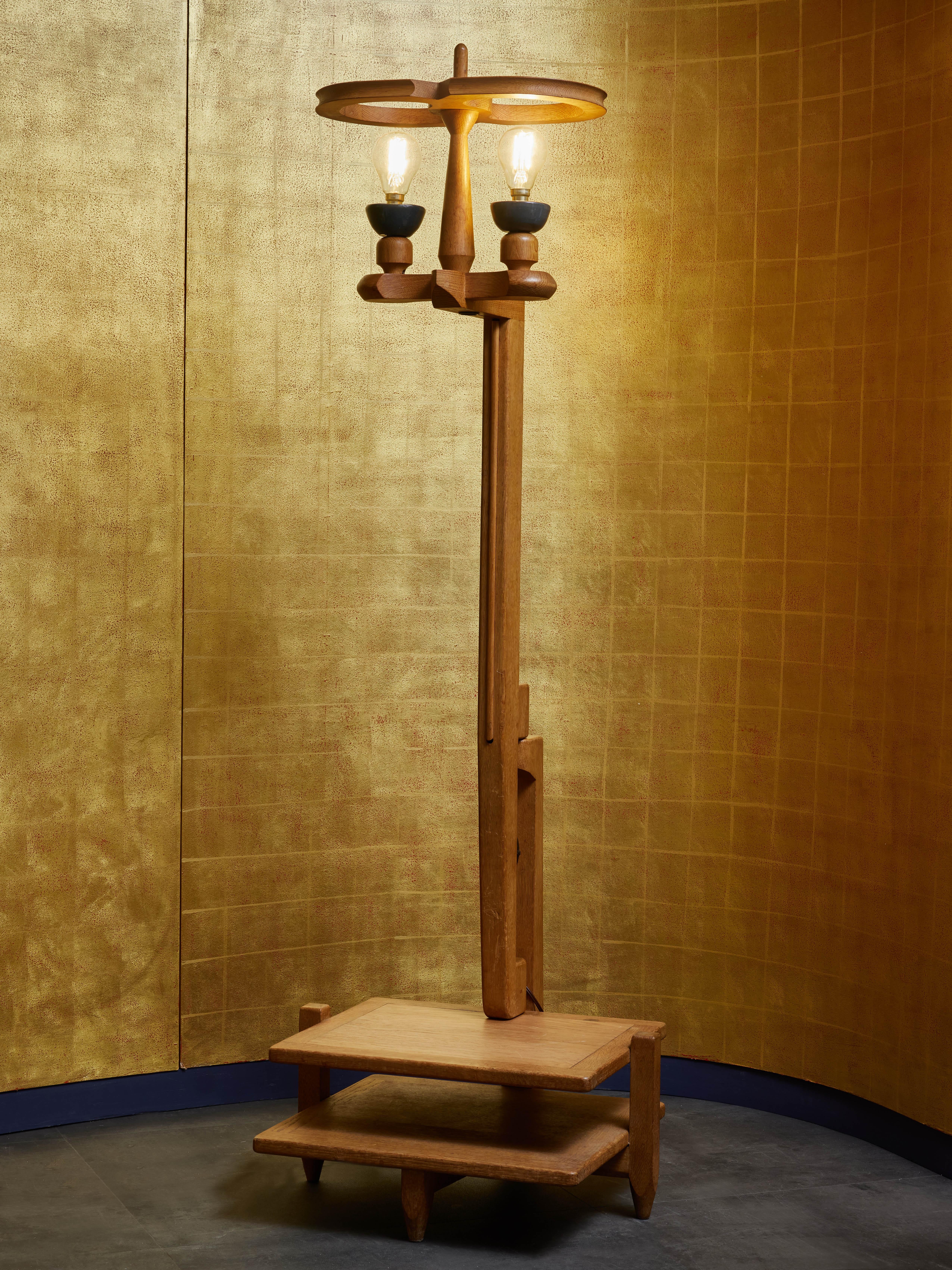 Vintage floor lamp designed by Guillerme et Chambron for their maison d'edition Votre Maison.

Made of oak wood, this floor lamp has a built in double tray at the bottom, rotating center piece and Danikowski ceramic bulb holder.