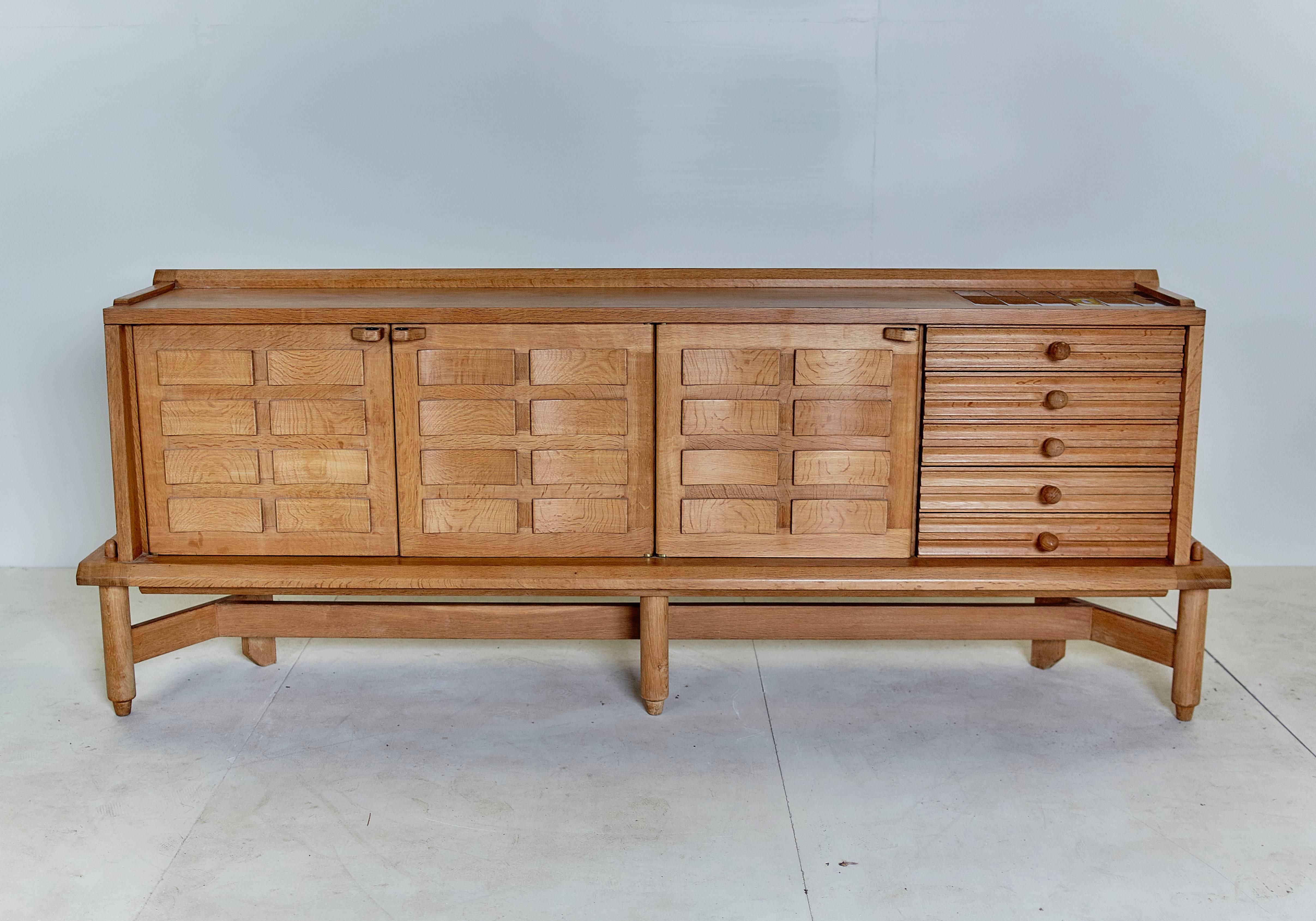 Beautiful and rare oak wall unit with two sliding doors and drawers, designed by the French Robert Guillerme and Jacques Chambron, from the 1960s. 
Typical decorations in ceramic tiles on the plateau on the right.

It is important to know that