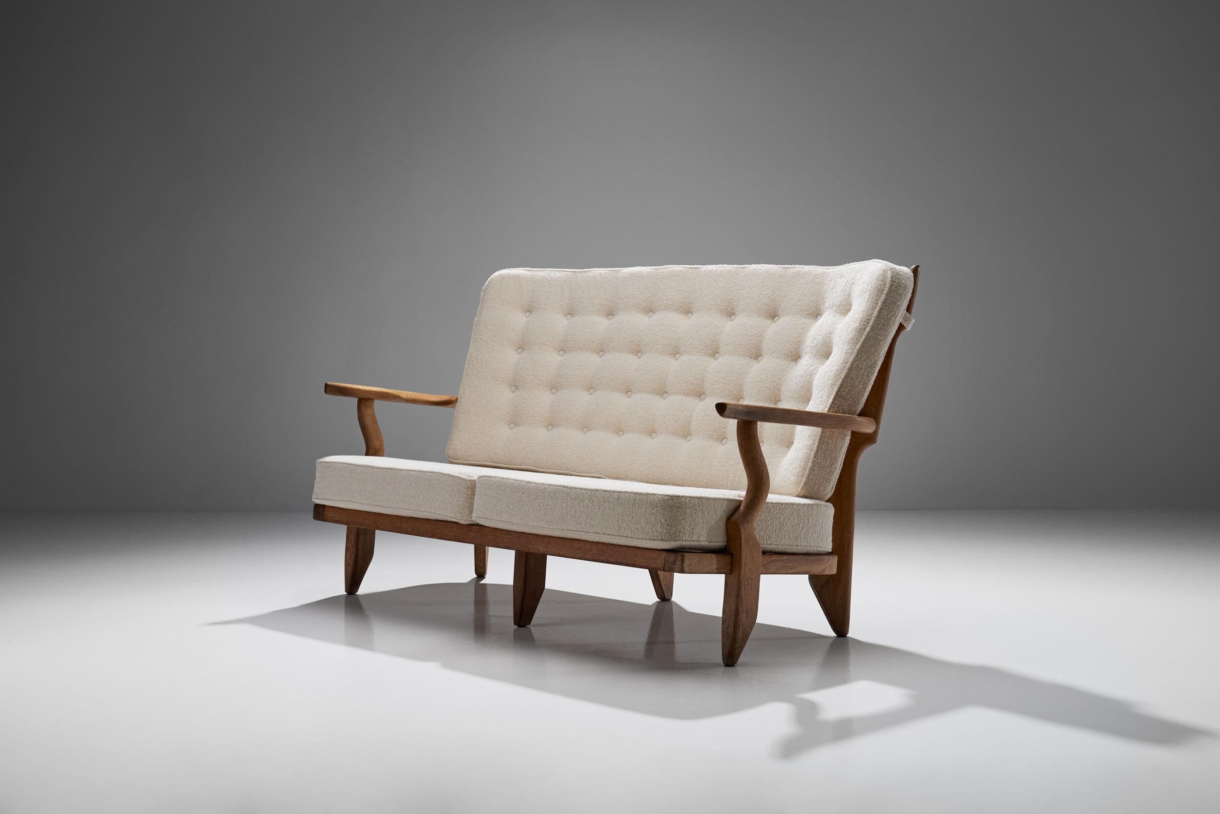 This Guillerme et Chambron Sofa displays a beautiful contrast between the light wooden oak frame and the elegant light fabric of the cushions. With a solid wooden frame, the support for the back consists of eleven wooden spindles extending upwards