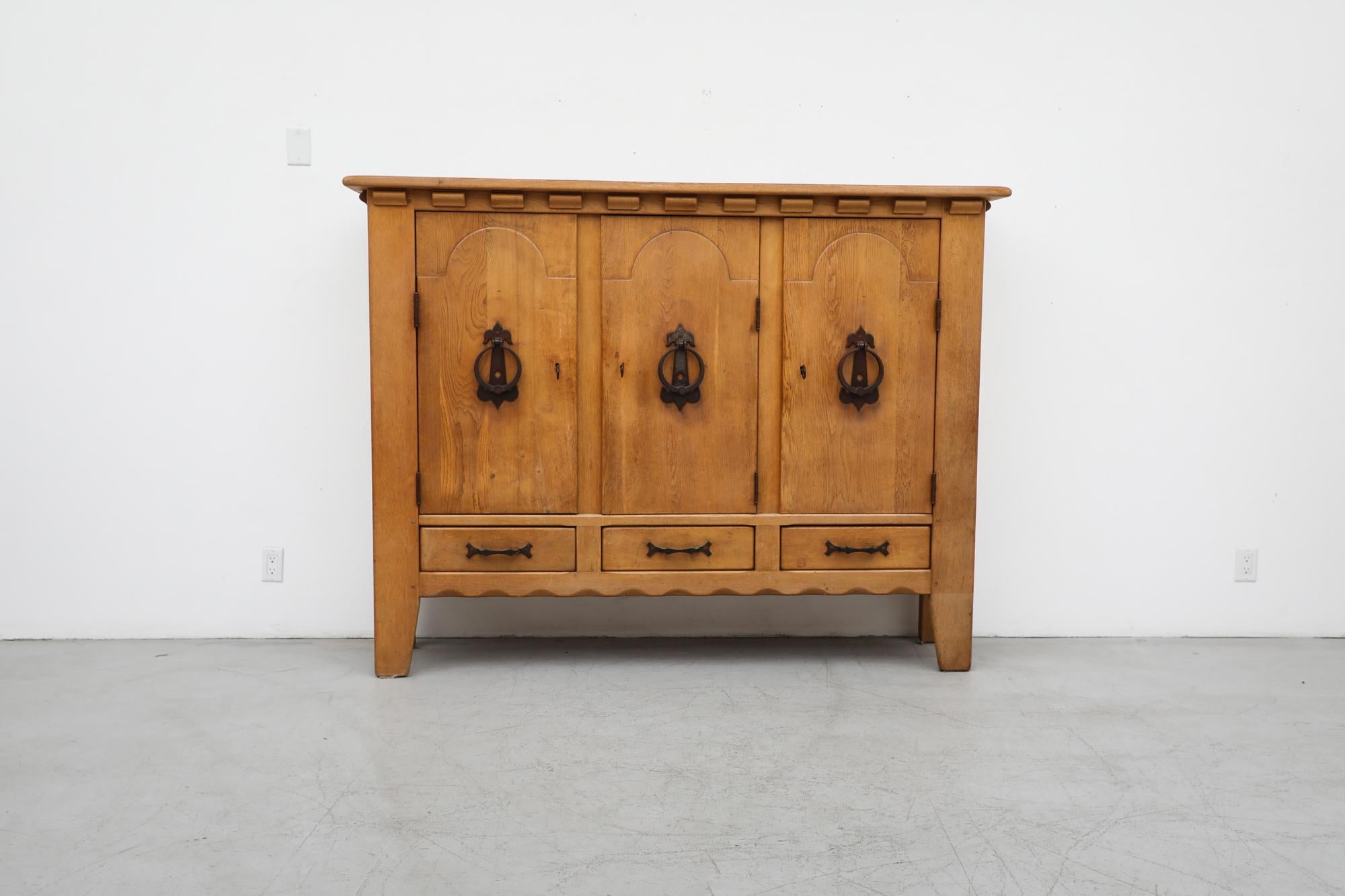Mid-Century Guillerme et Chambron Inspired large brutalist solid oak sideboard with iron hardware by Sprij Meubelen. This high sideboard has shelving inside the cabinets and three lower drawers. Cabinet doors lock with large iron keys. In original