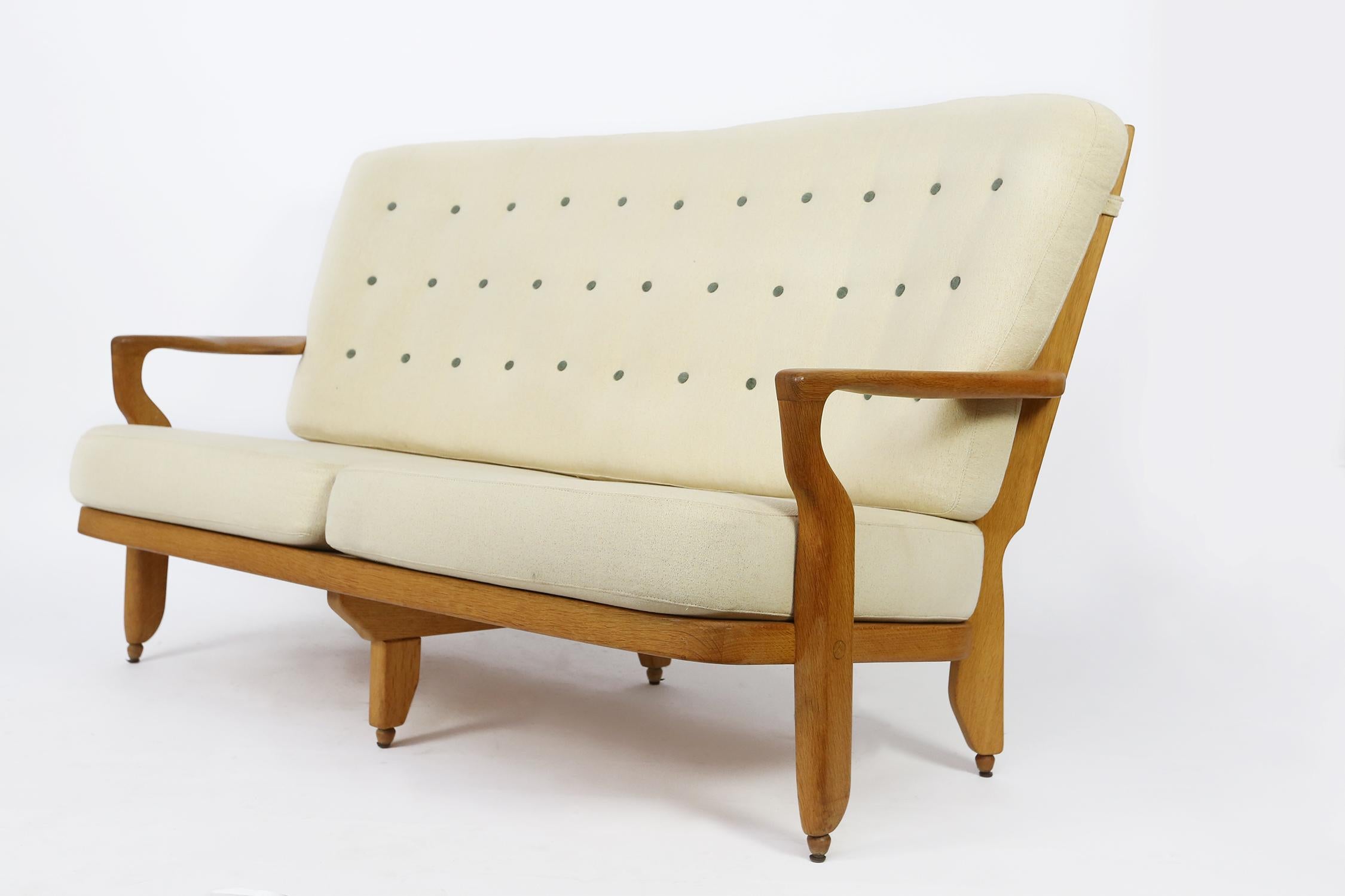 Sofa by French midcentury designers Robert Guillerme and Jacques Chambron, for Votre Maison 1960s in solid oak and with fabric cushions.
This Guillerme et Chambron sofa displays a beautiful contrast between the light wooden oak frame and the