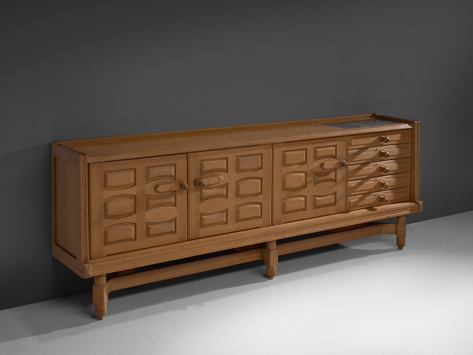 Guillerme and Chambron, large sideboard in oak, France, 1960s.

This large sideboard is designed by Guillerme and Chambron and features geometric engravings in the three front doors that offers plenty of storage. On the right, the cabinet features