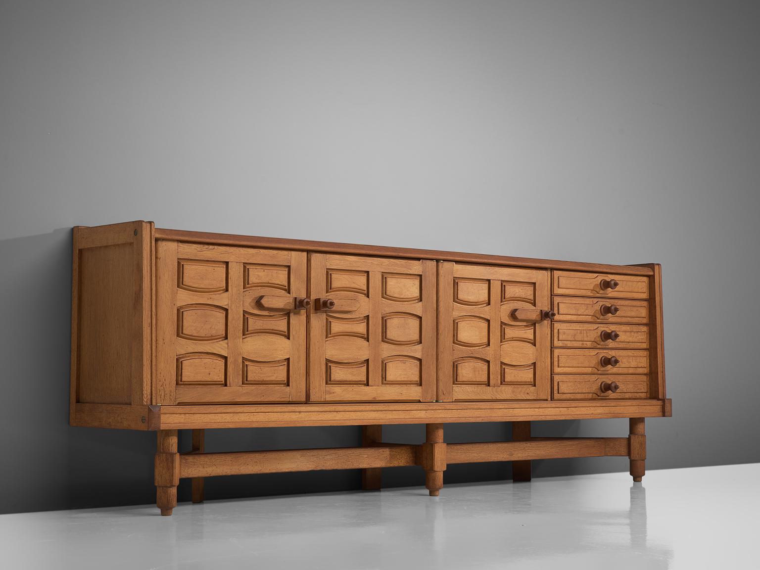 Guillerme and Chambron, large sideboard in oak, France, 1960s.

This large sideboard is designed by Guillerme and Chambron and features geometric engravings in the three front doors that offers plenty of storage. On the right, the cabinet features