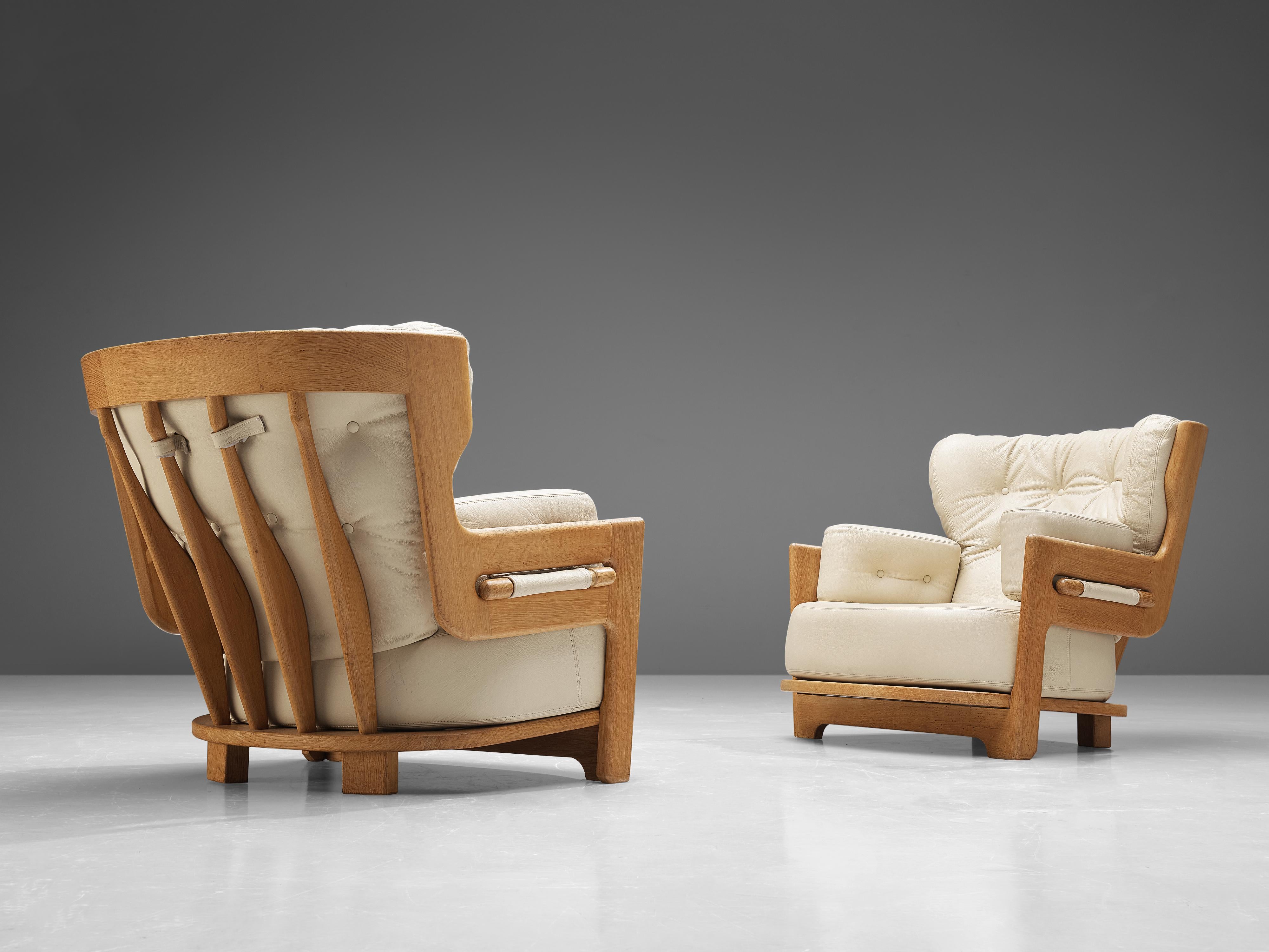 Guillerme et Chambron for Votre Maison, lounge chairs 'Denis', leather, oak, France, 1960s 

Extraordinary Guillerme and Chambron lounge chairs in solid oak with the typical characteristic decorative details at the back and capricious forms of the