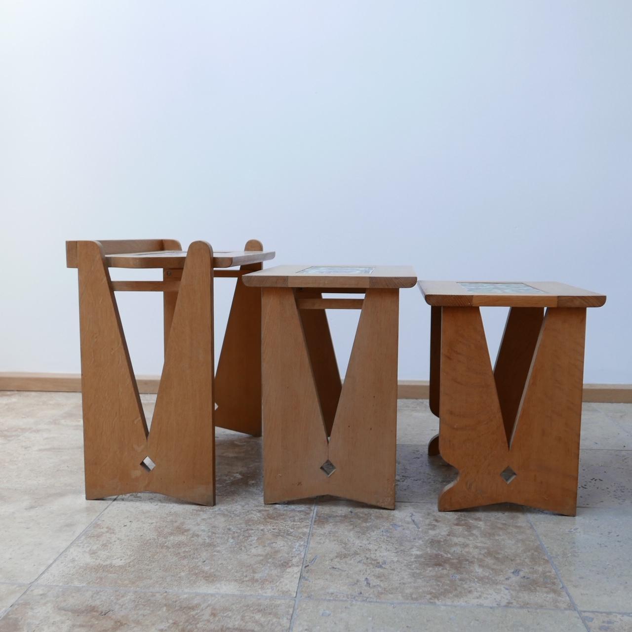 A trio of nesting tables by French design legends Guillerme et Chambron.

French, circa 1960s.

Retaining their original ceramics, which can easily be replaced with mirror or smoked glass to taste.

The tables are formed from oak, and the