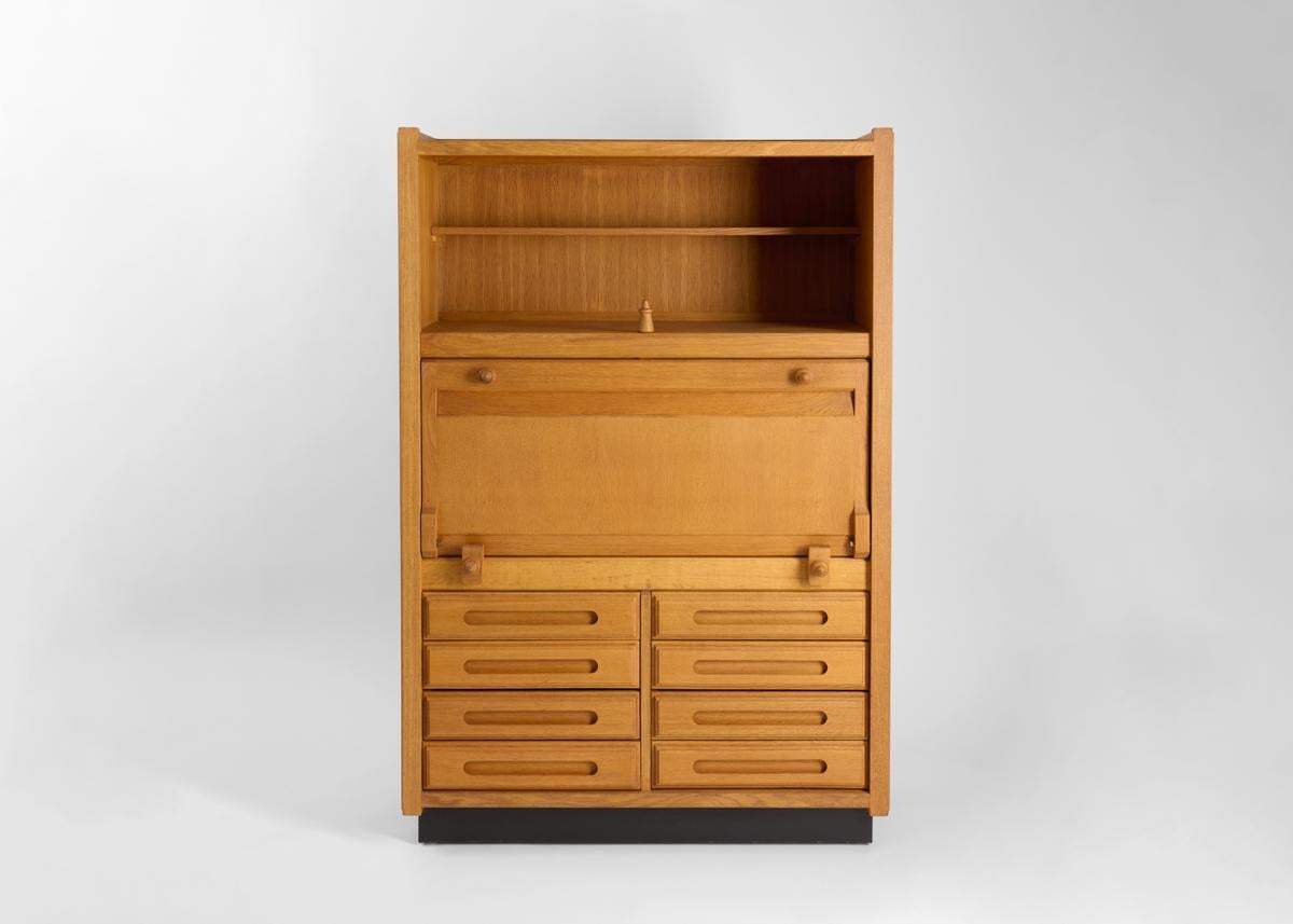 This midcentury, polished light oak secretary by the celebrated French designer Robert Guillerme, was created as part of a line of design he produced for the company Votre Maison. When dropped, the top reveals several shelves. The lower part of the