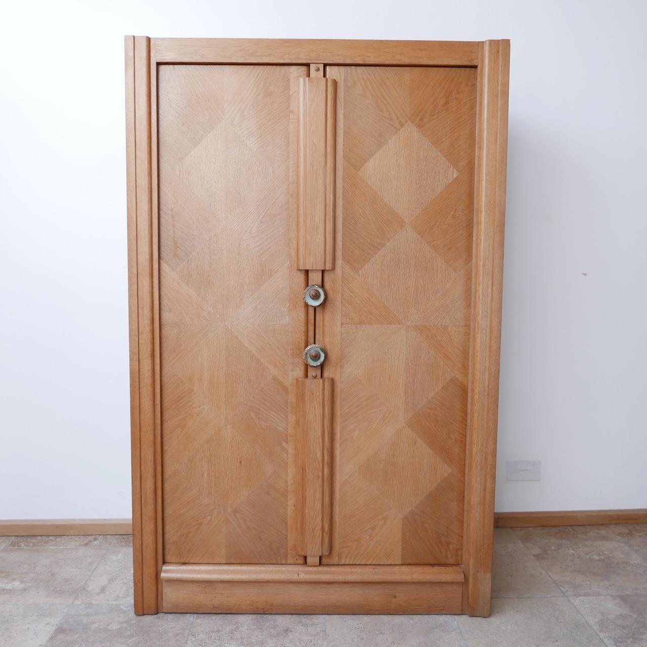 A two door cabinet/wardrobe from design legends Guillerme et Chambron. 

France, c1960s. 

Oak with original ceramic handles. 

Generally good condition, some wear commensurate with age. 

Dimensions: 110 W x 47.5 D x 173 H in cm.