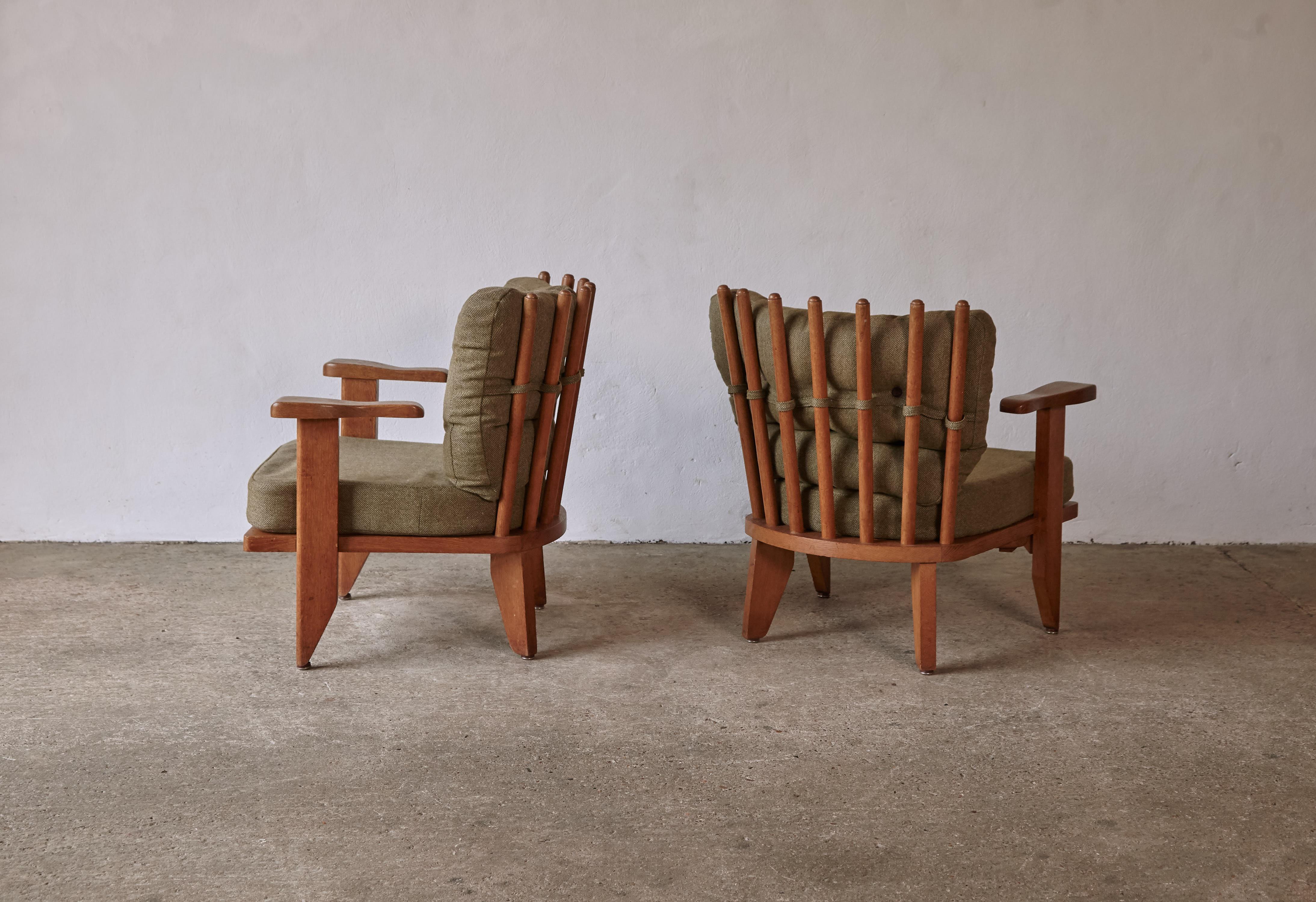 A rare pair of Guillerme et Chambron low lounge chairs / armchairs, oak, fabric, France, 1960s. Edition Votre Maison.  Small optional drinks side table that slides out from under each chair.   Good original condition.   The cushions have one very