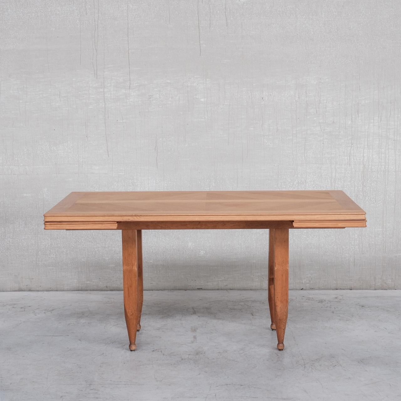 A rectangular mid-century oak dining table. 

France, c1960s. 

Featuring cleverly designed and hidden extendable sheafs that are easy to install quickly. 

The table remains in good condition, there are some scuffs and wear commensurate with