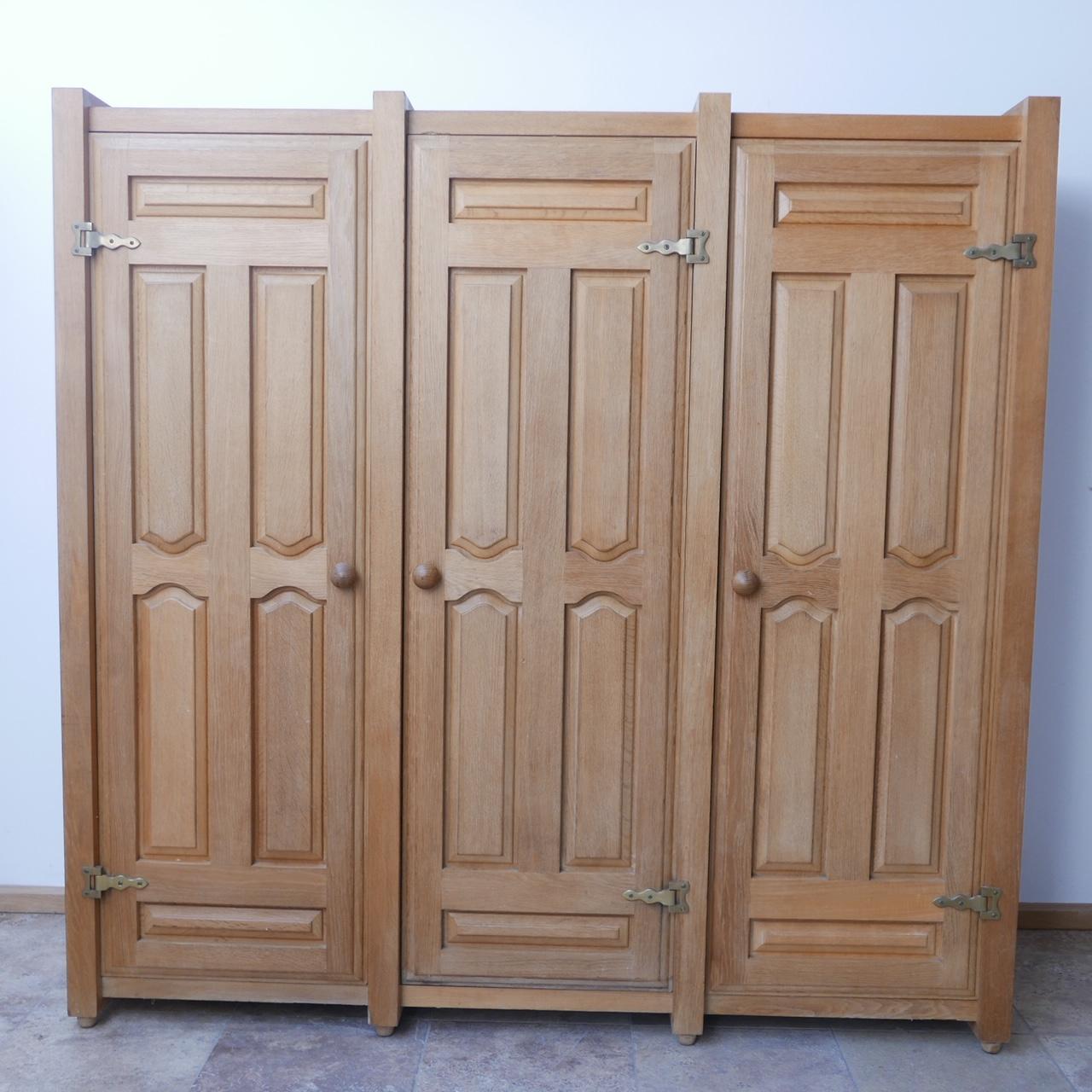A three door cabinet/wardrobe from design legends Guillerme et Chambron. 

France, c1960s. 

Oak and brass. 

Generally good condition, some wear commensurate with age. 

Dimensions: 183 W x 53 D x 180 H in cm.

Delivery: POA.

 