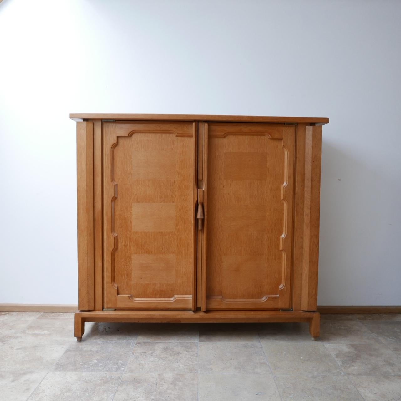 A scarce cabinet by Guillerme et Chambron. 

Oak, France, c1960s. 

'Bouvine' model. 

Two secret side doors hide additional storage, internally there are shelves.

Clever wooden locking mechanism, with thick brass exposed hinges. 

Good