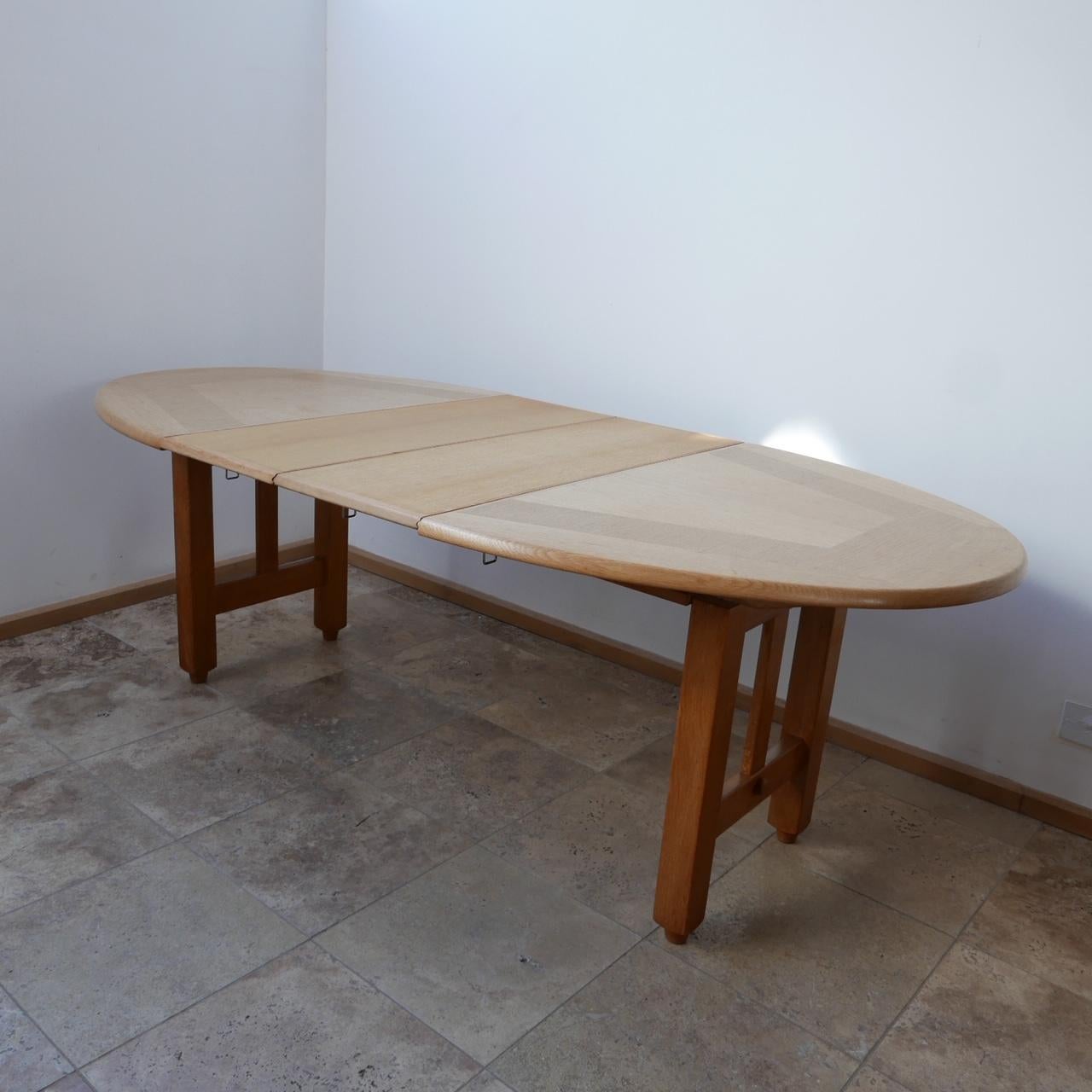 An adjustable dining table by design legends Guillerme et Chambron. 

France, c1970s. 

Two optional extendable leaves. 

Good vintage condition. 

The leaves add 35 cm per leaf. So up to 70 total extension. 

Dimensions: 74 H x 103 D x