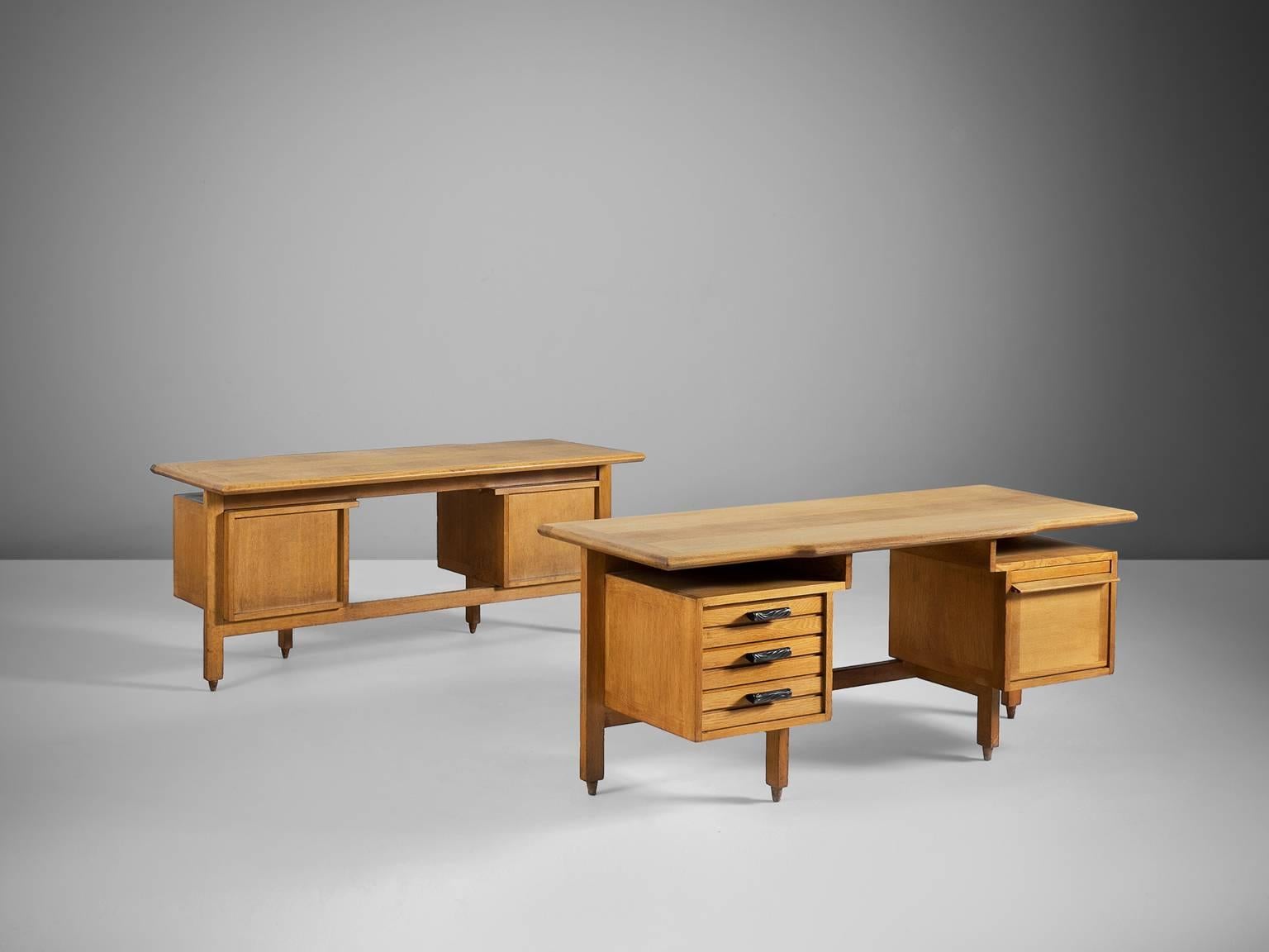 Guillerme et Chambron, set of oak desks, France, 1950s.

This desk has a large work surface and are equipped with plenty of storage space due well decorated drawers with ceramic handles on the left and one large compartment on the right. It even