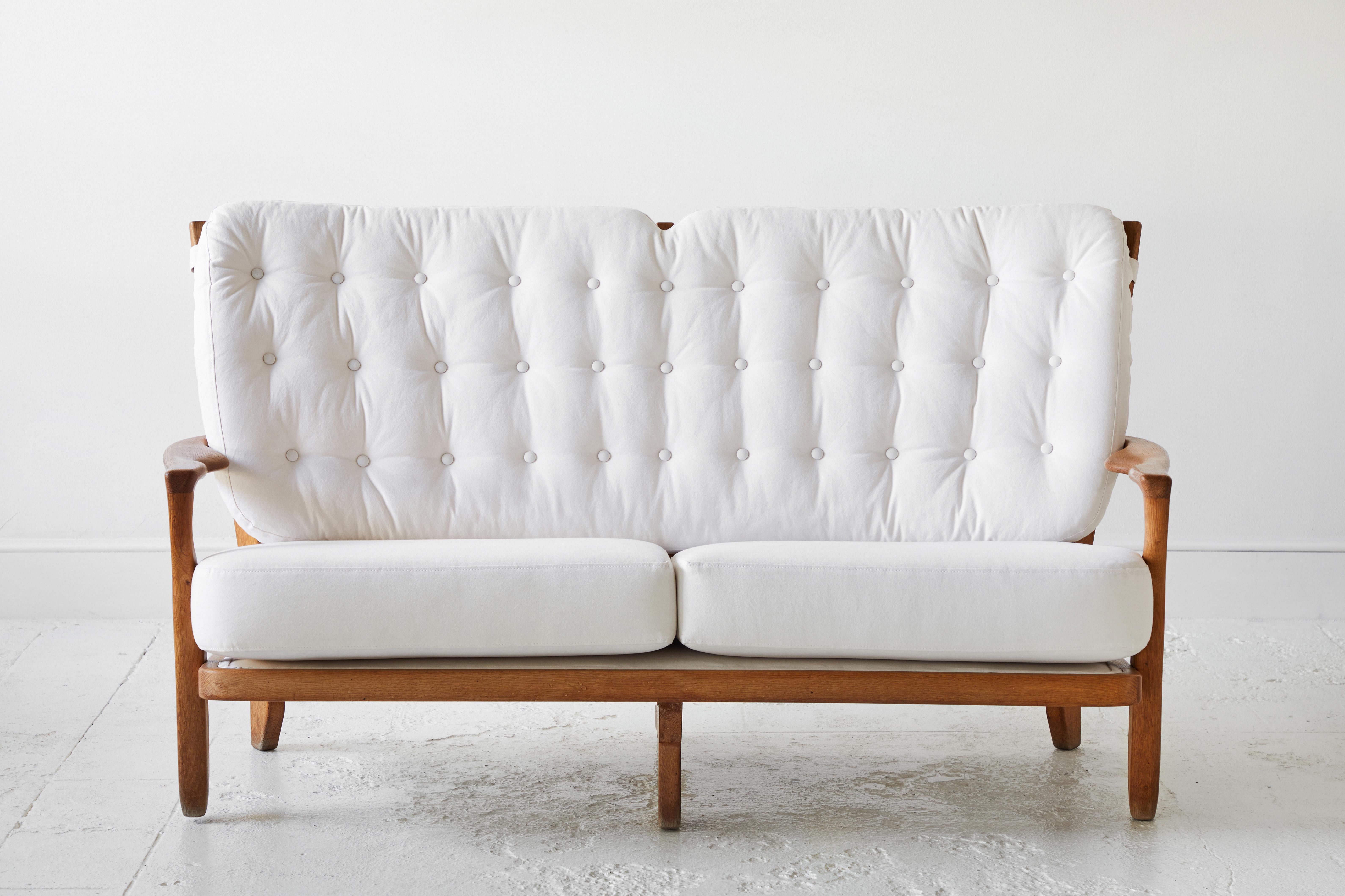 Guillerme and Chambron, upholstered in a white stonewash cotton, oak, France, 1950s

This sculptural carved oak settee is designed by Guillerme and Chambron. The design duo is known for their sculptural, crafted solid oak furniture. This
