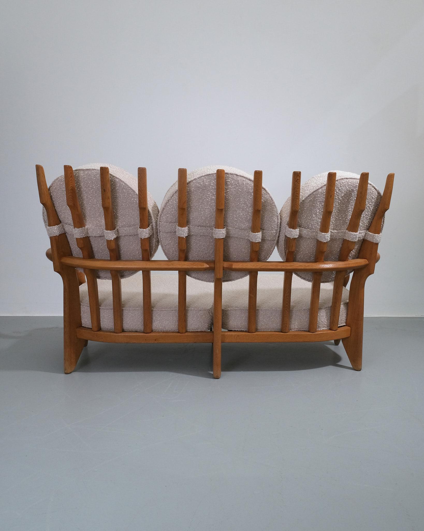 A beautifully sculptural sofa by French designers Guillerme et Chambron, c.1960s, featuring their signature solid oak frame with a distinctive slatted backrest. The duo, known for their masterful craftsmanship and bold, architectural forms, were