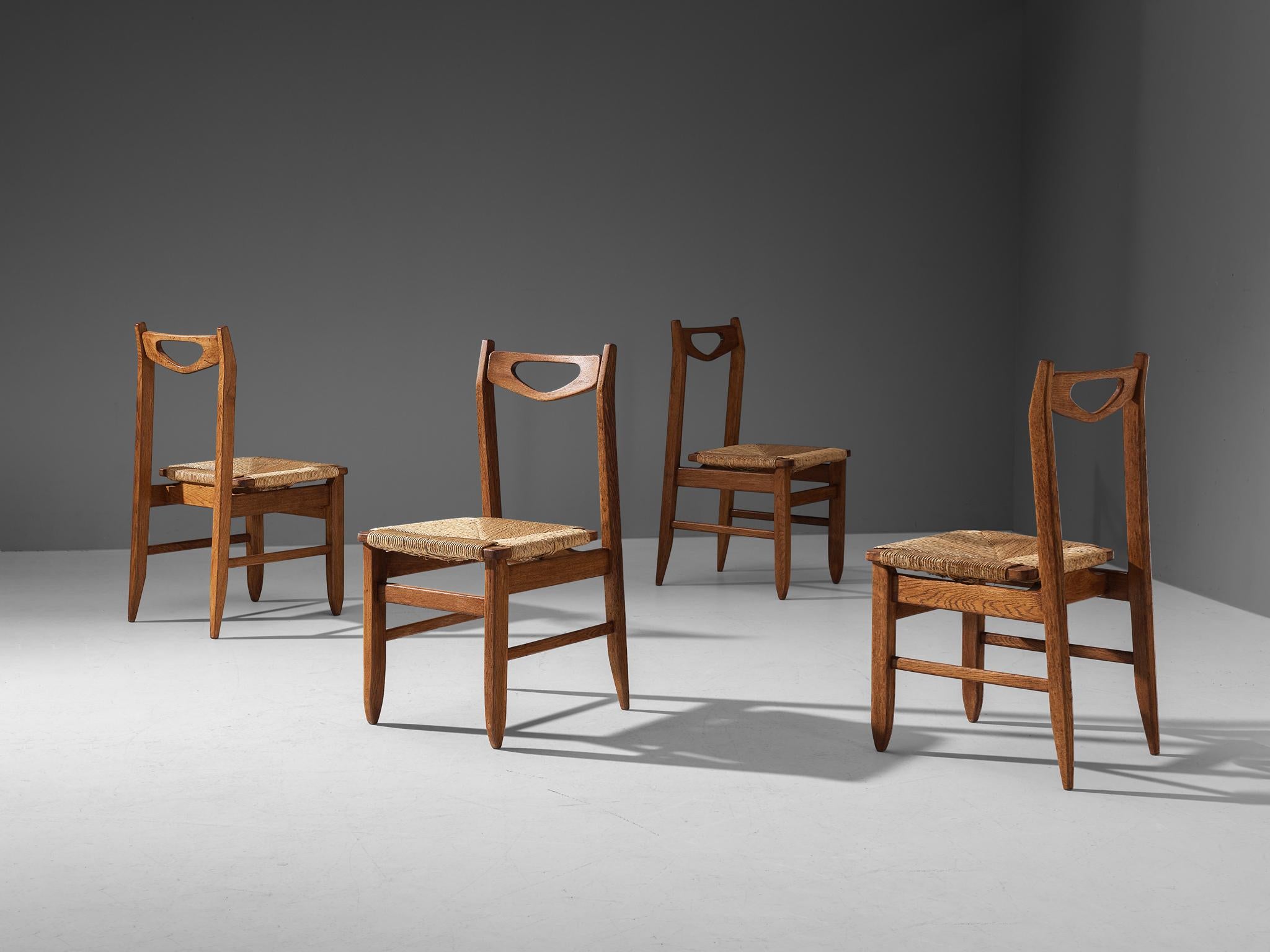 Guillerme & Chambron for Votre Maison, dining chairs, oak, straw, France, 1960s

Set of four elegant dining chairs in solid oak by Guillerme and Chambron. These chairs show the characteristic frame of this French designer duo. The backrest