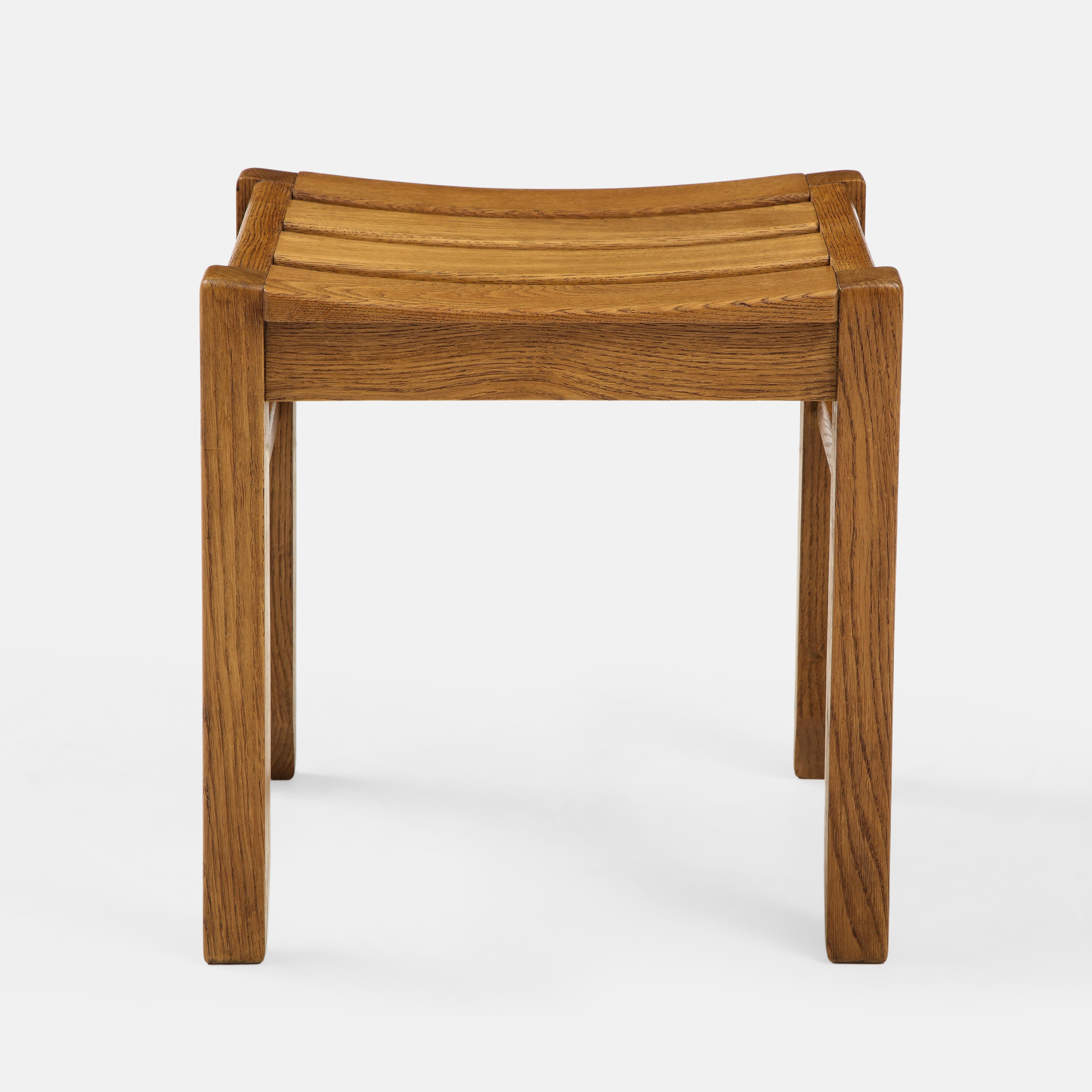 Guillerme et Chambron for Edition Votre Maison solid oak stool with elegant sculptural form, France, 1950s. The stool's composition is playfully graphic with the top composed of slightly curved slats and legs angled towards the bottom giving it an
